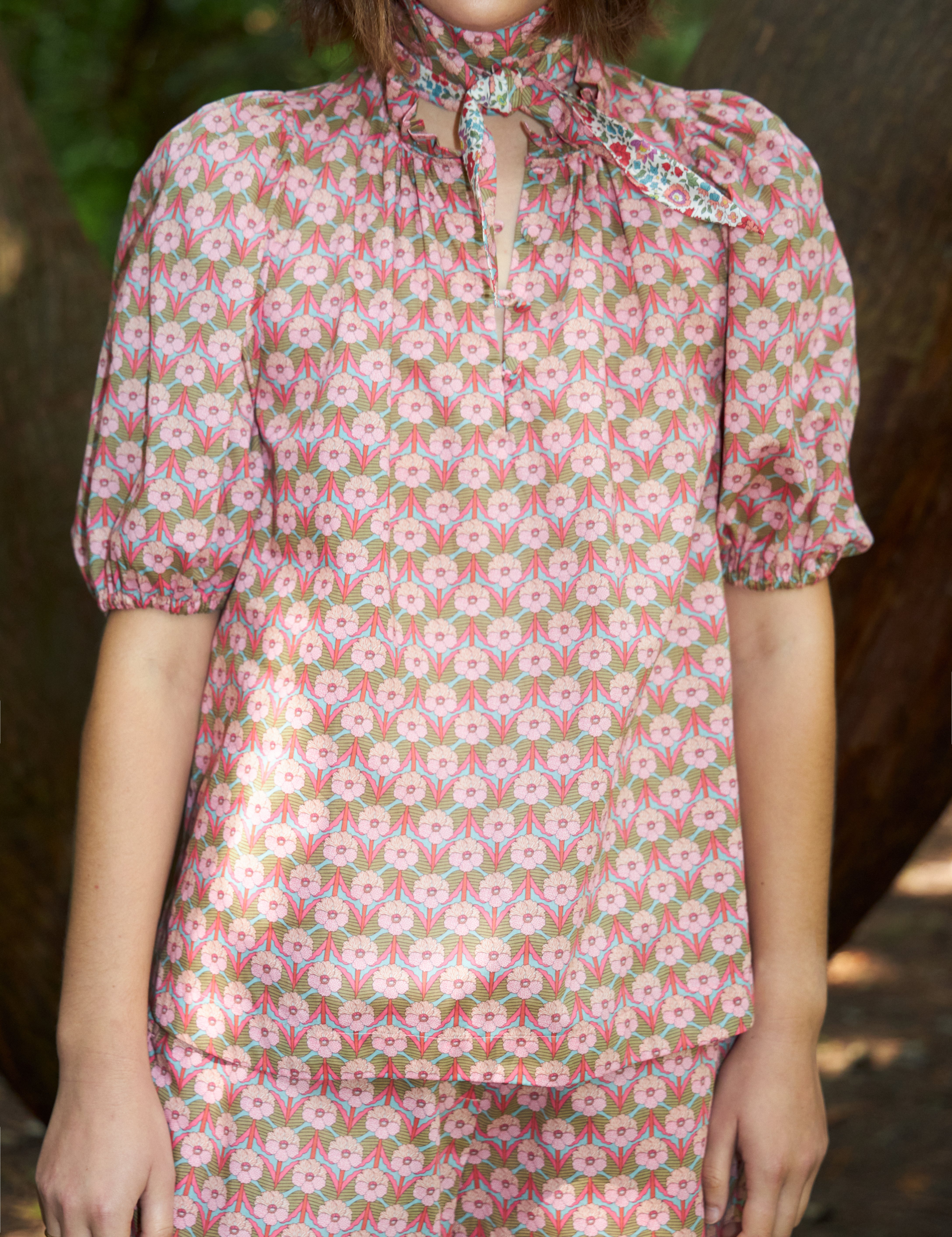 Woman in pink flower print blouse with short puff sleeves and matching shorts