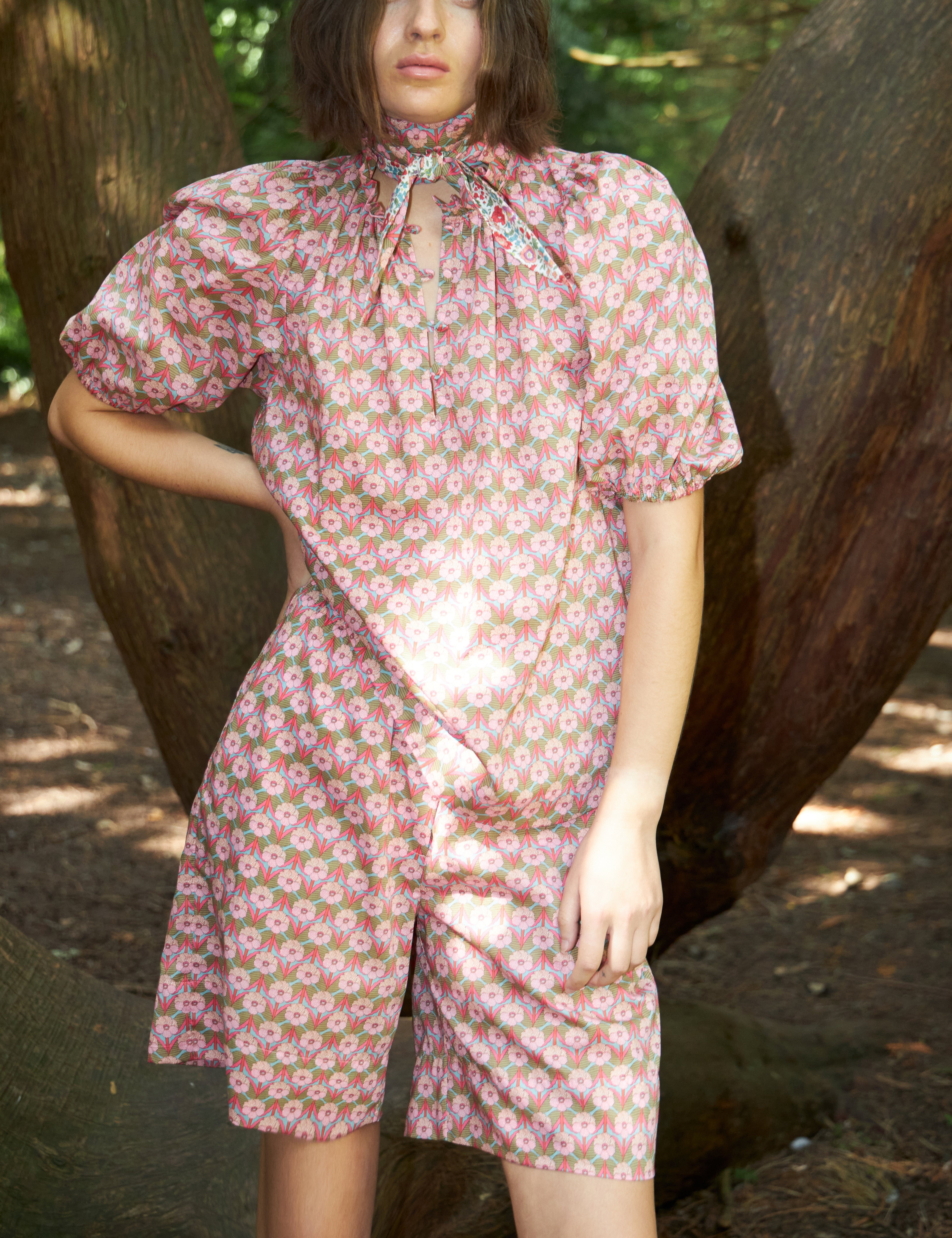 Woman in pink flower print blouse with short puff sleeves and matching shorts