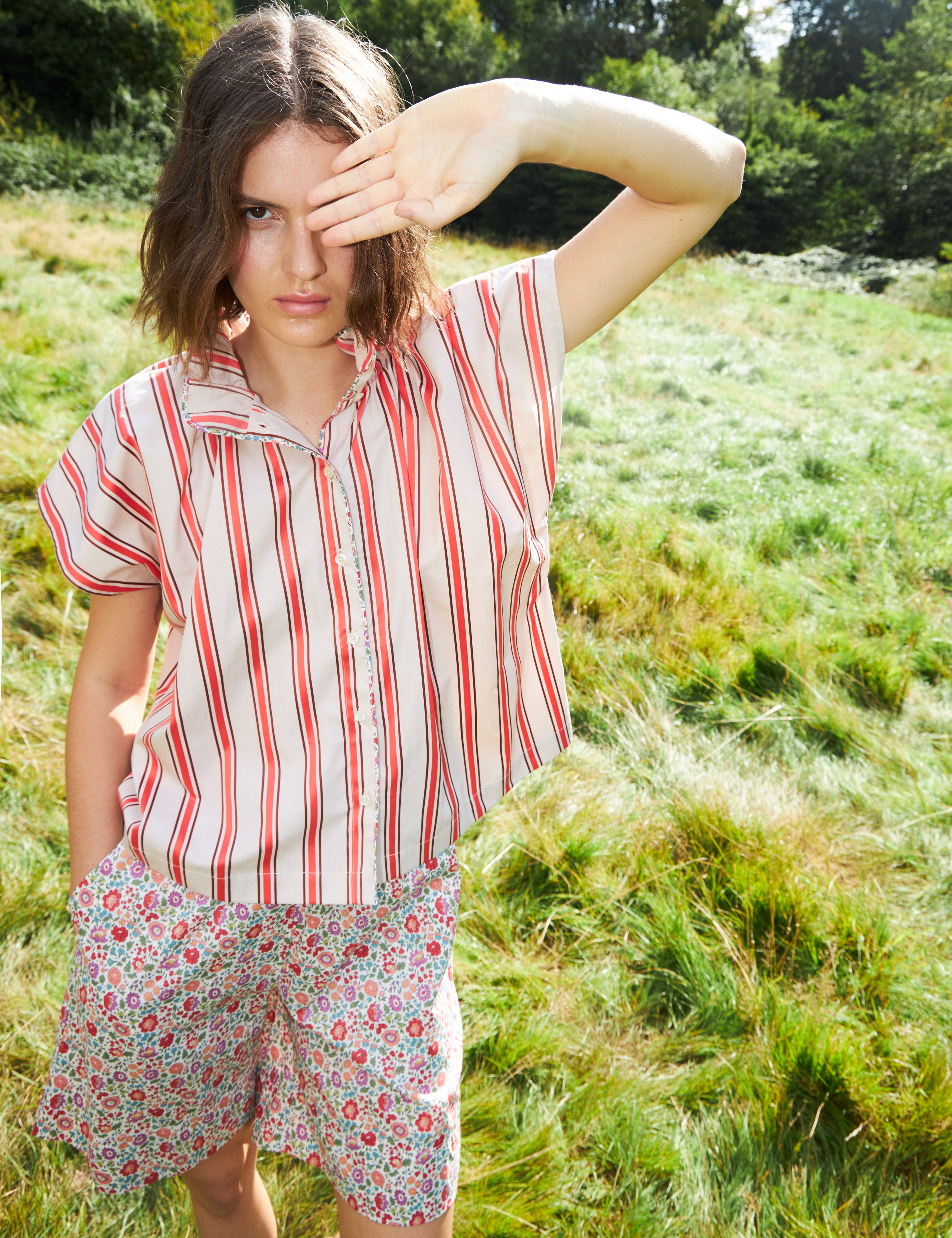 Woman in red and white striped sleeveless top with stand collar and shorts with multi-colored small flower pattern