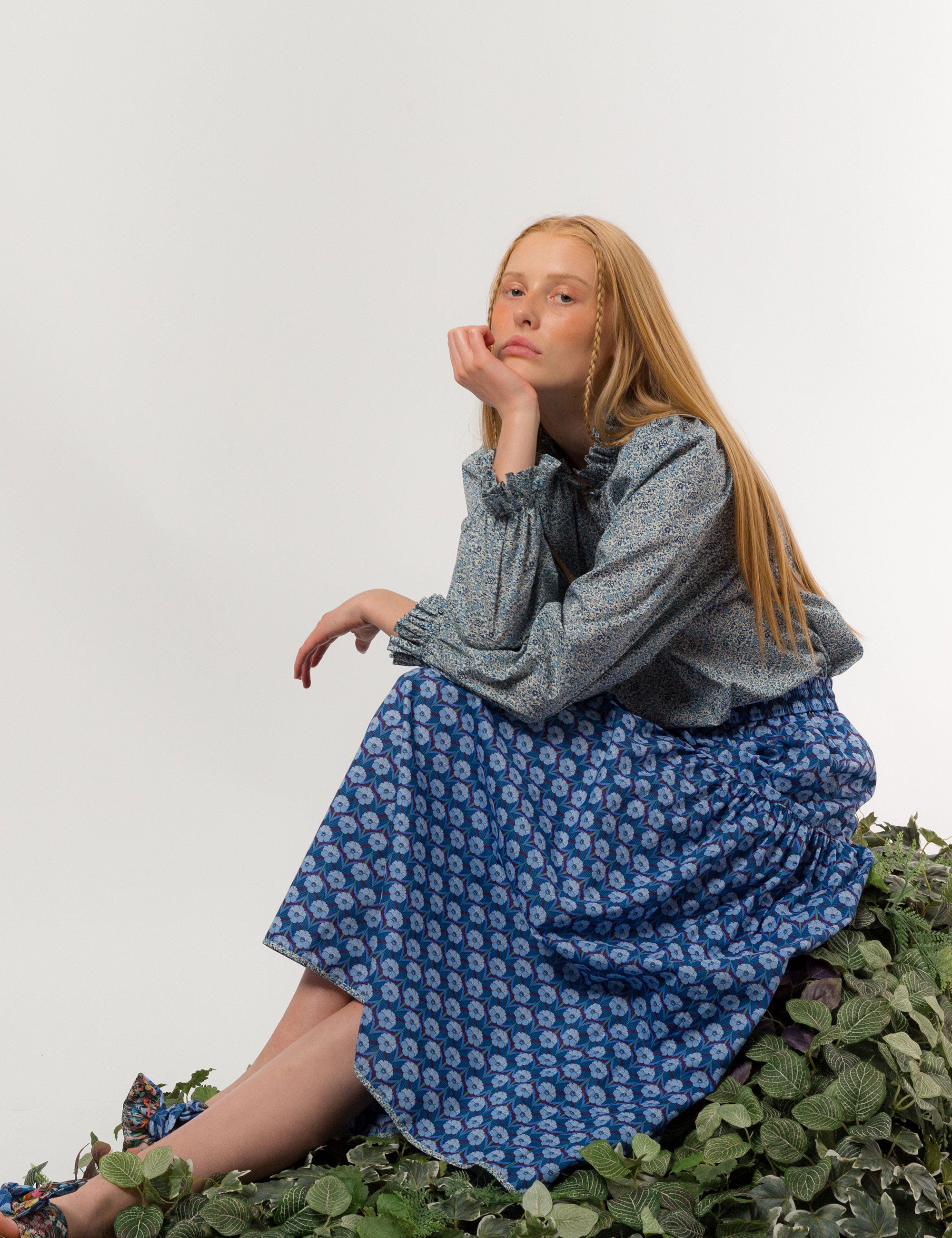 Woman in liberty cotton small blue floral print shirt with frilled cuffs and collar and long sleeves and blue floral skirt