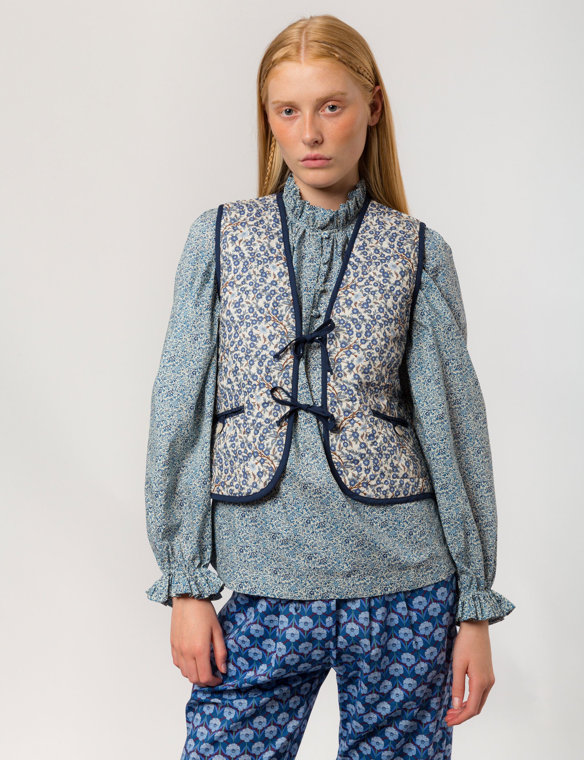 Woman in reversible liberty cotton blue and white floral print vest with buttons, pockets and blue pipings, blue floral shirt and blue floral print pants
