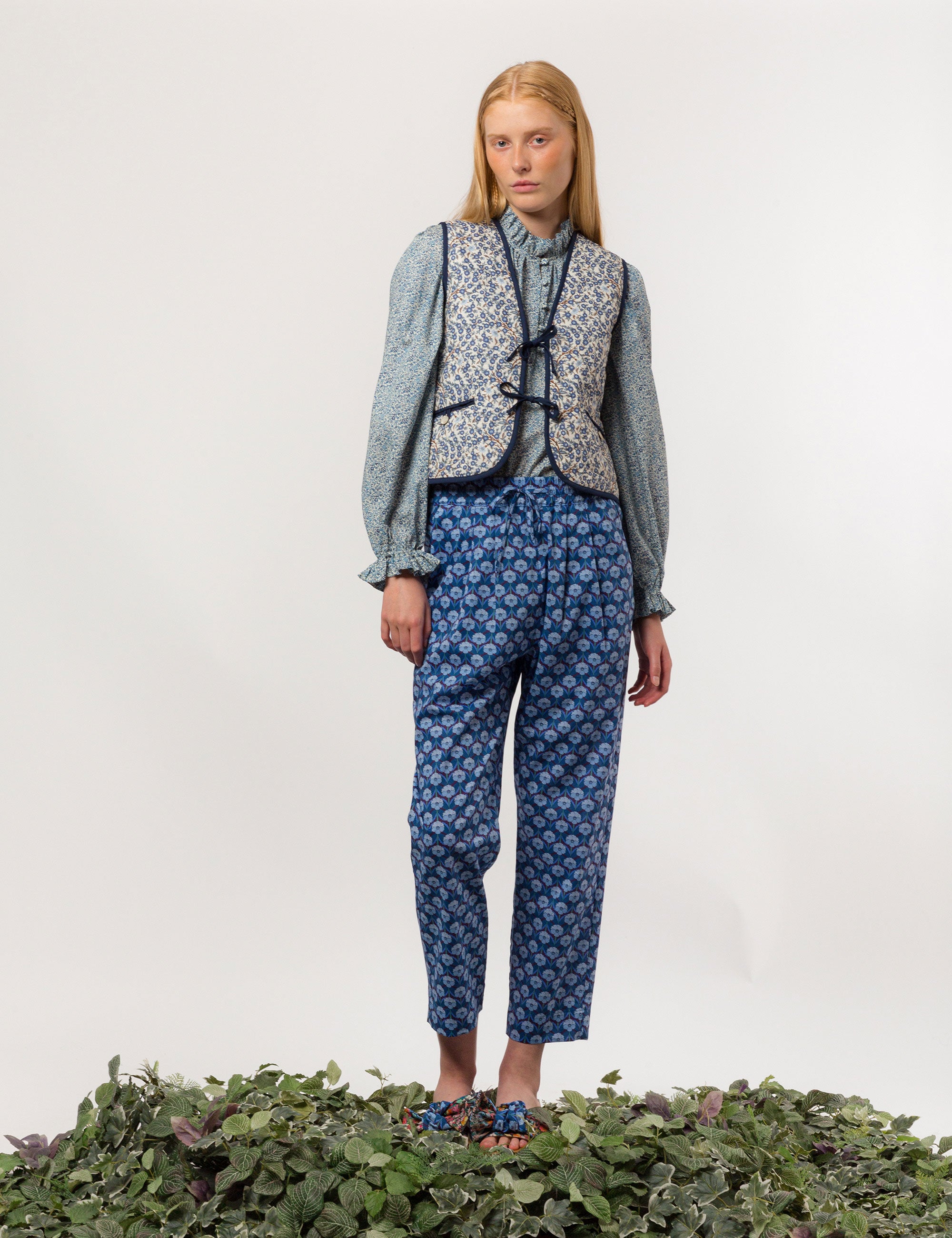 Woman in reversible liberty cotton blue and white floral print vest with buttons, pockets and blue pipings, blue floral shirt and blue floral print pants