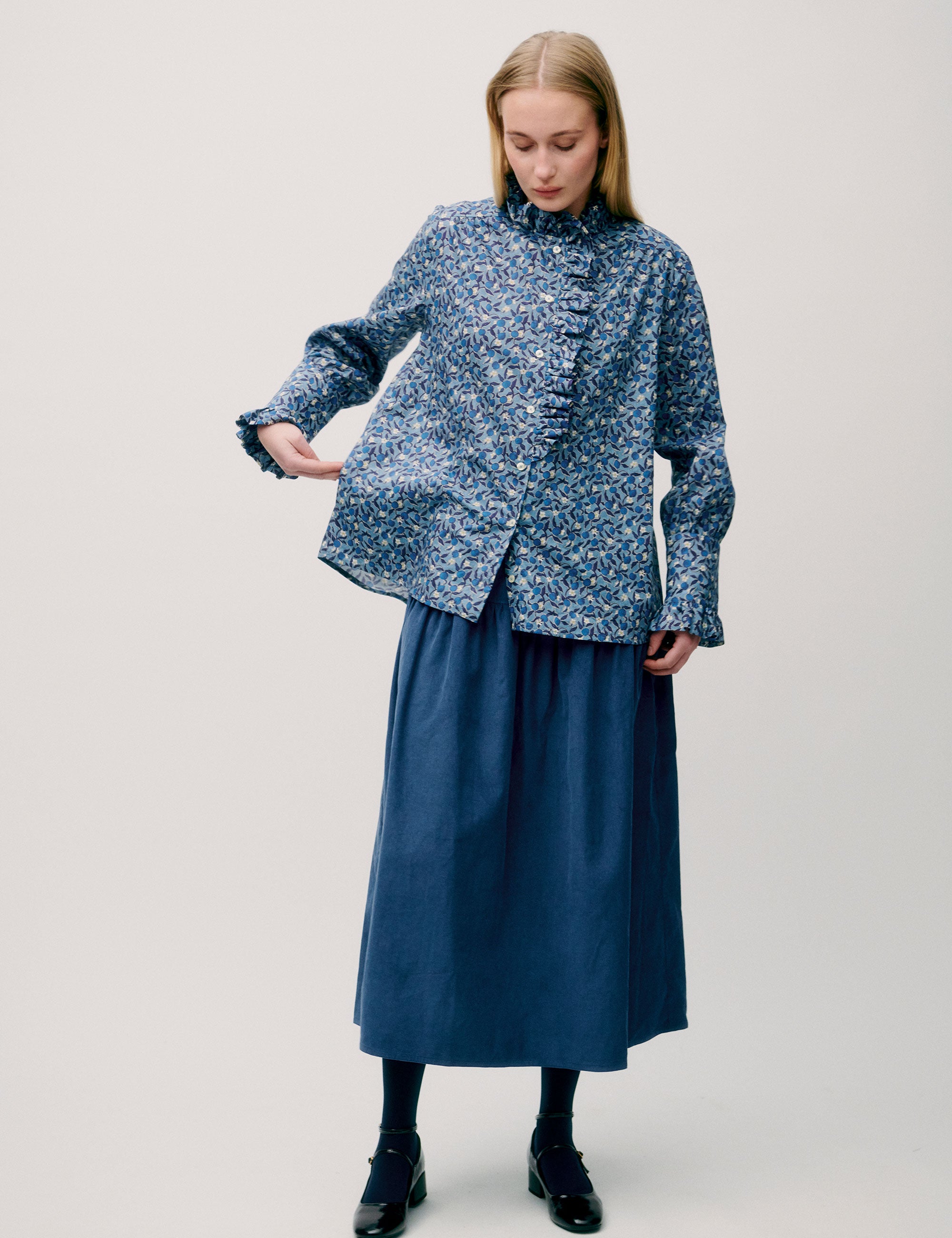 Woman in blue floral blouse and skirt, posing from side view
