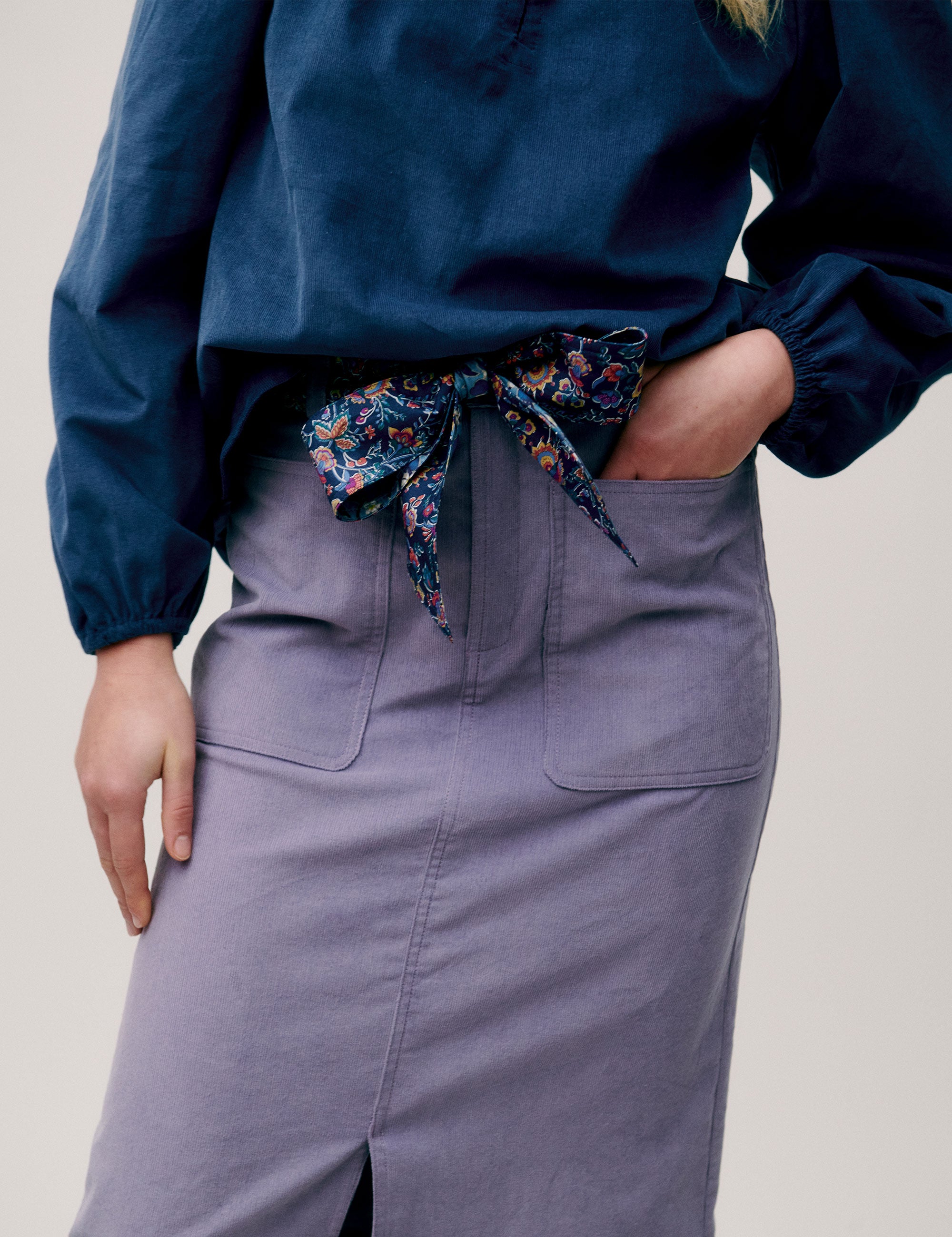 Close-up of blue blouse and lavender skirt with floral scarf belt