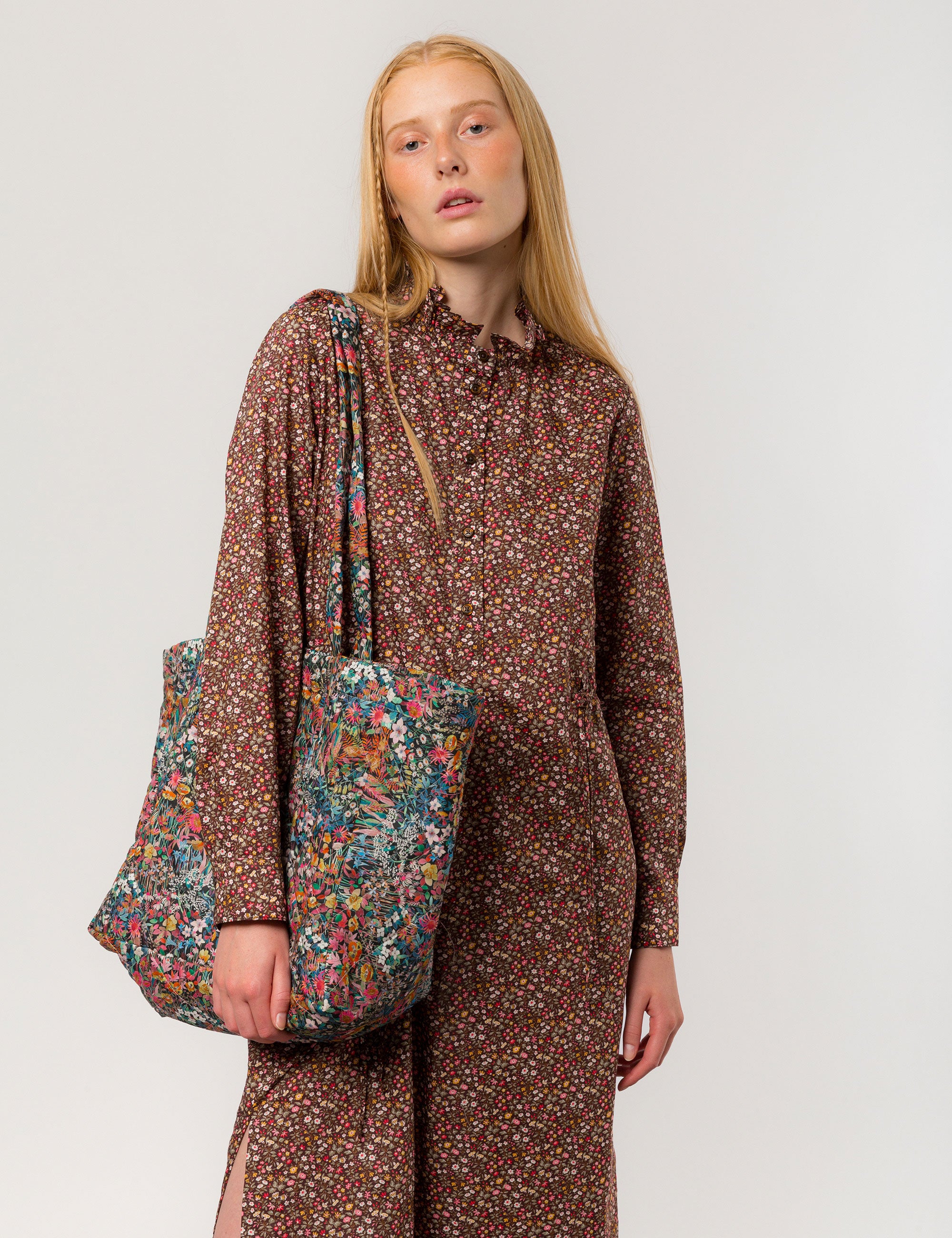Woman in brown floral print dress carrying a tote in Liberty cotton floral print that is reversible
