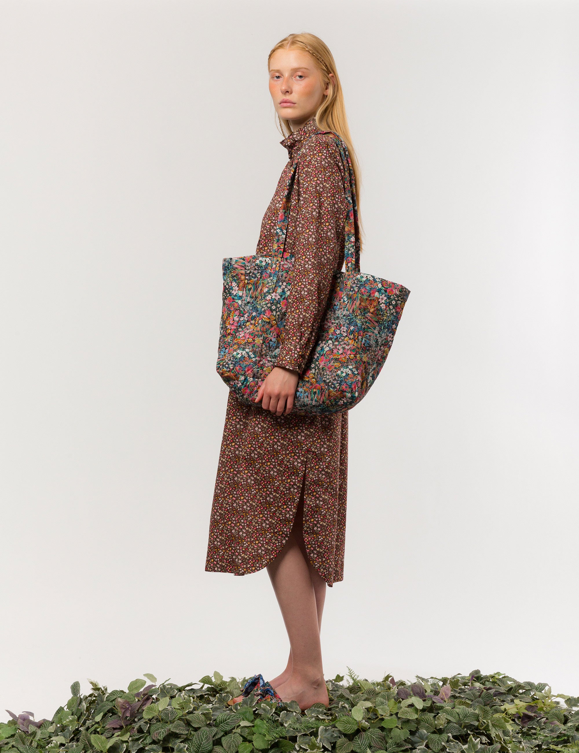Woman in brown floral print dress carrying a tote in Liberty cotton floral print that is reversible