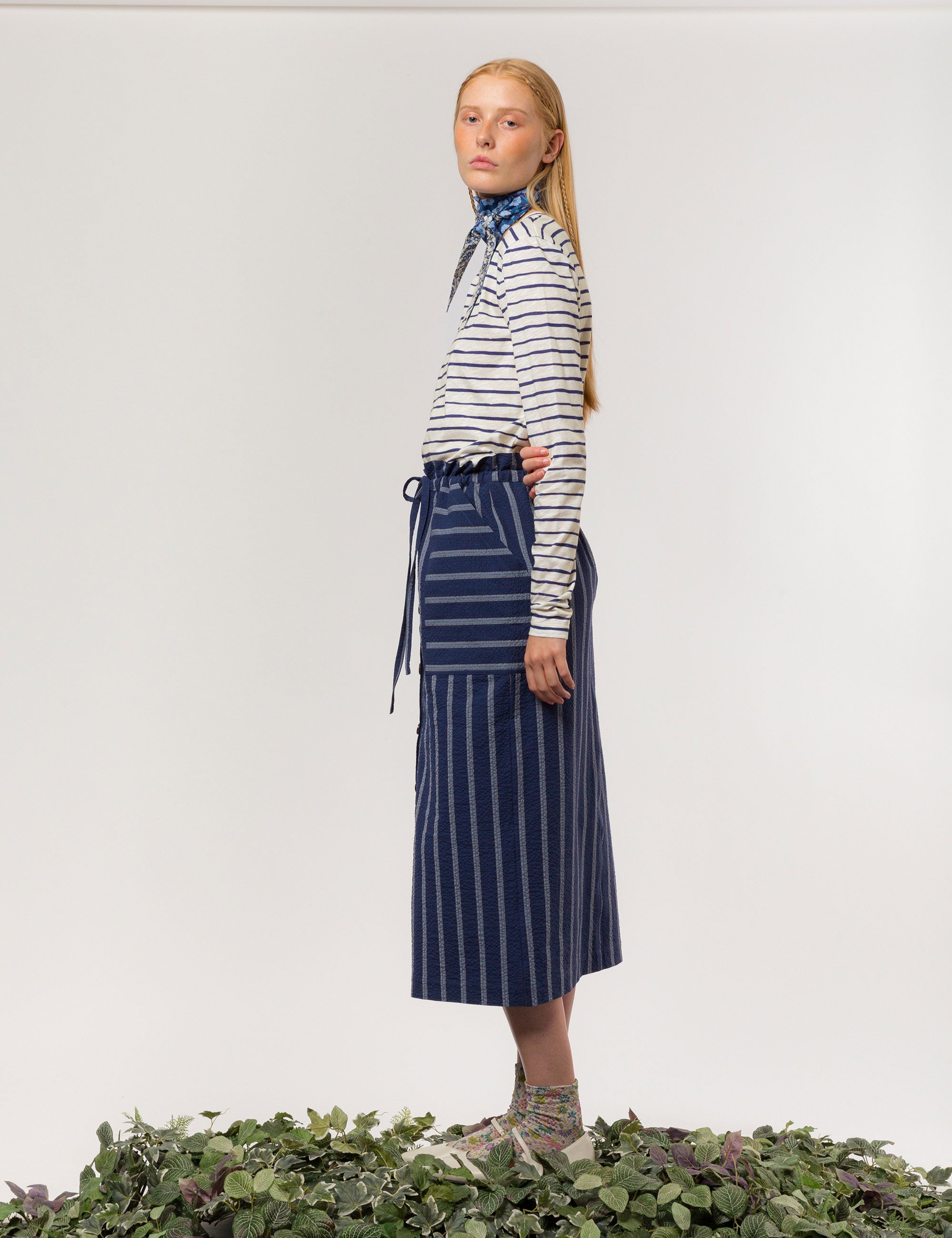 Woman in white and blue striped skirt with pockets and long sleeved t-shirt with blue and white stripes