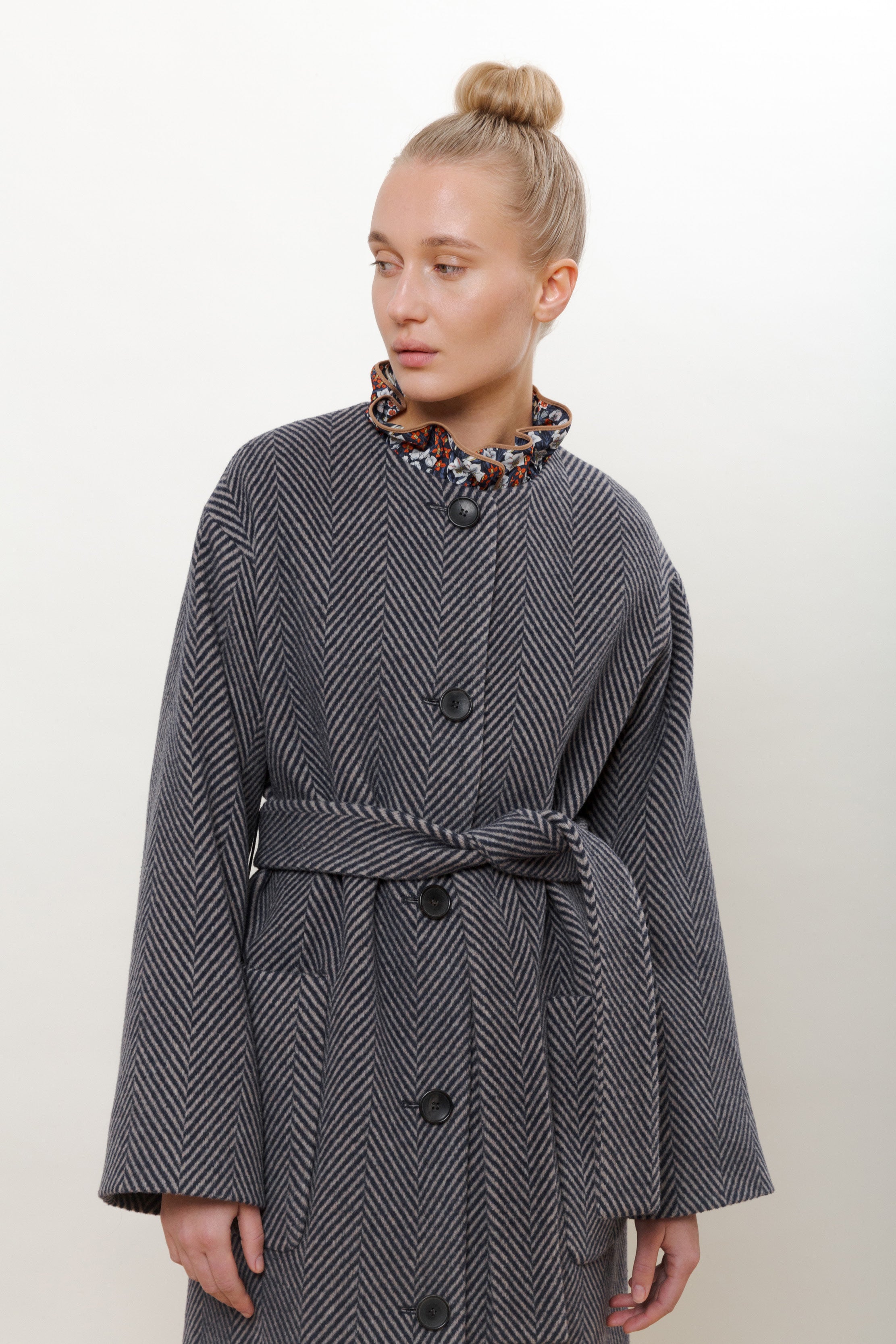 Woman in blue herringbone coat with belt and buttons
