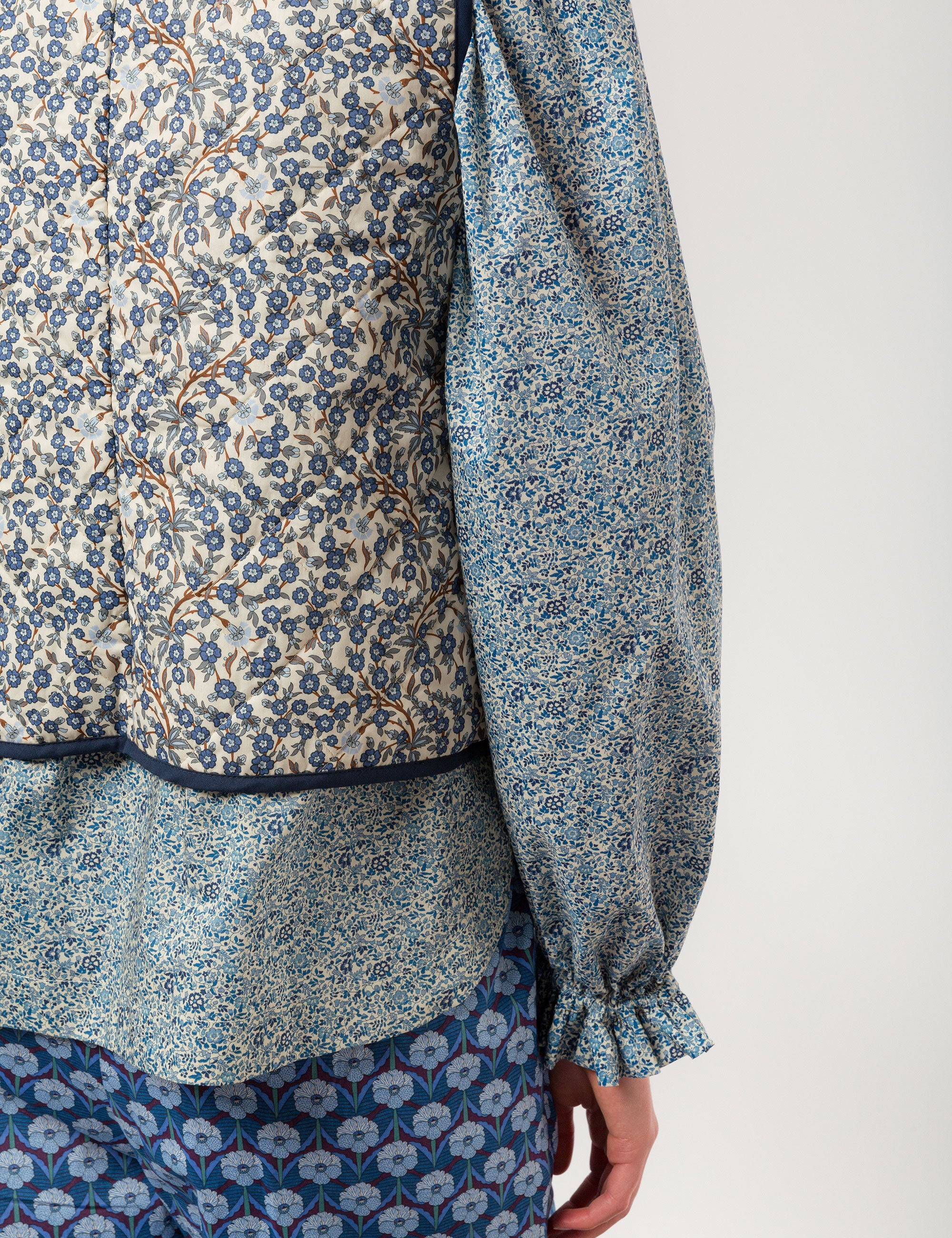 Woman in reversible liberty cotton blue and white floral print vest with buttons, pockets and blue pipings, blue floral shirt and blue floral print pants