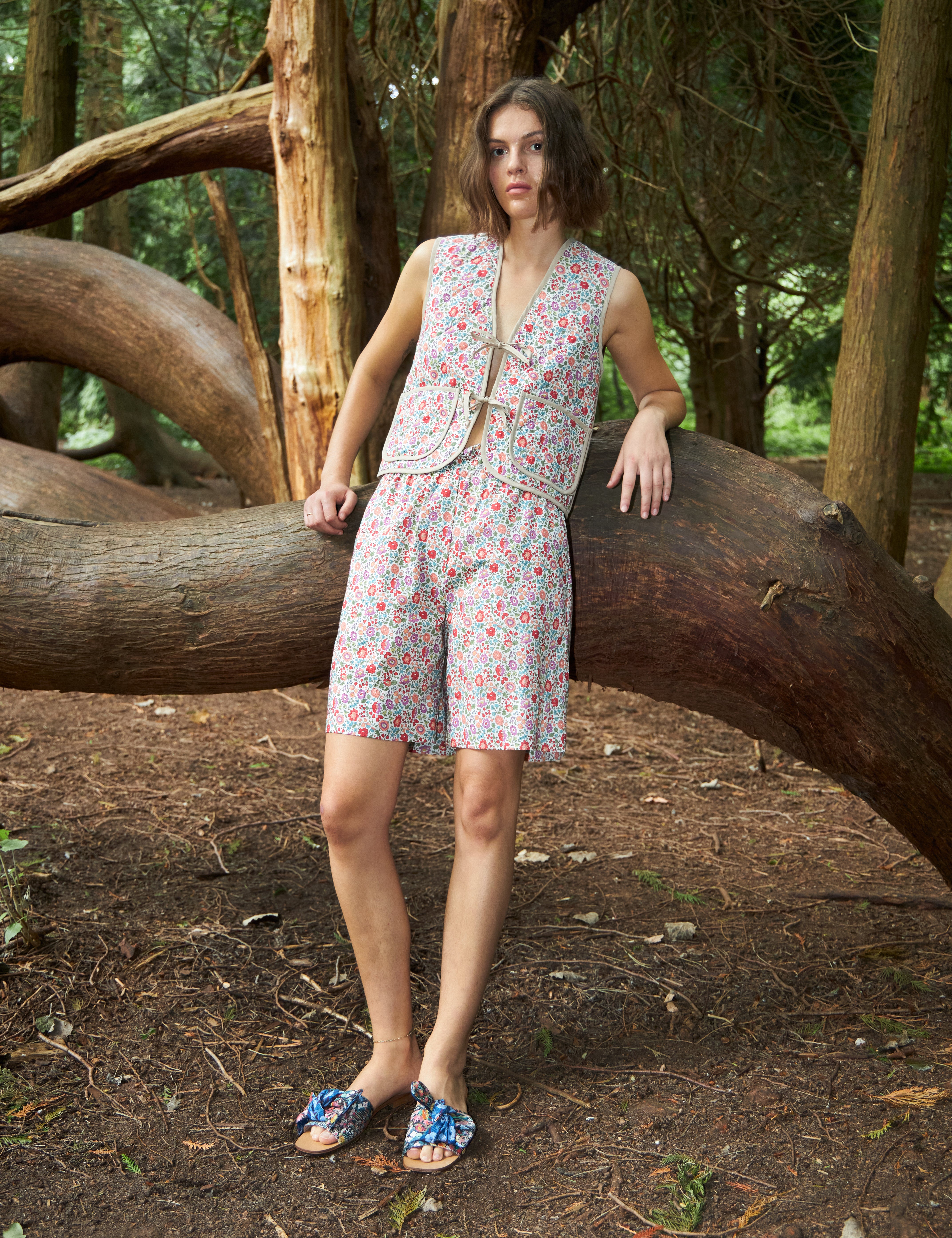 Woman in multi-colored floral print vest with pockets and matching shorts