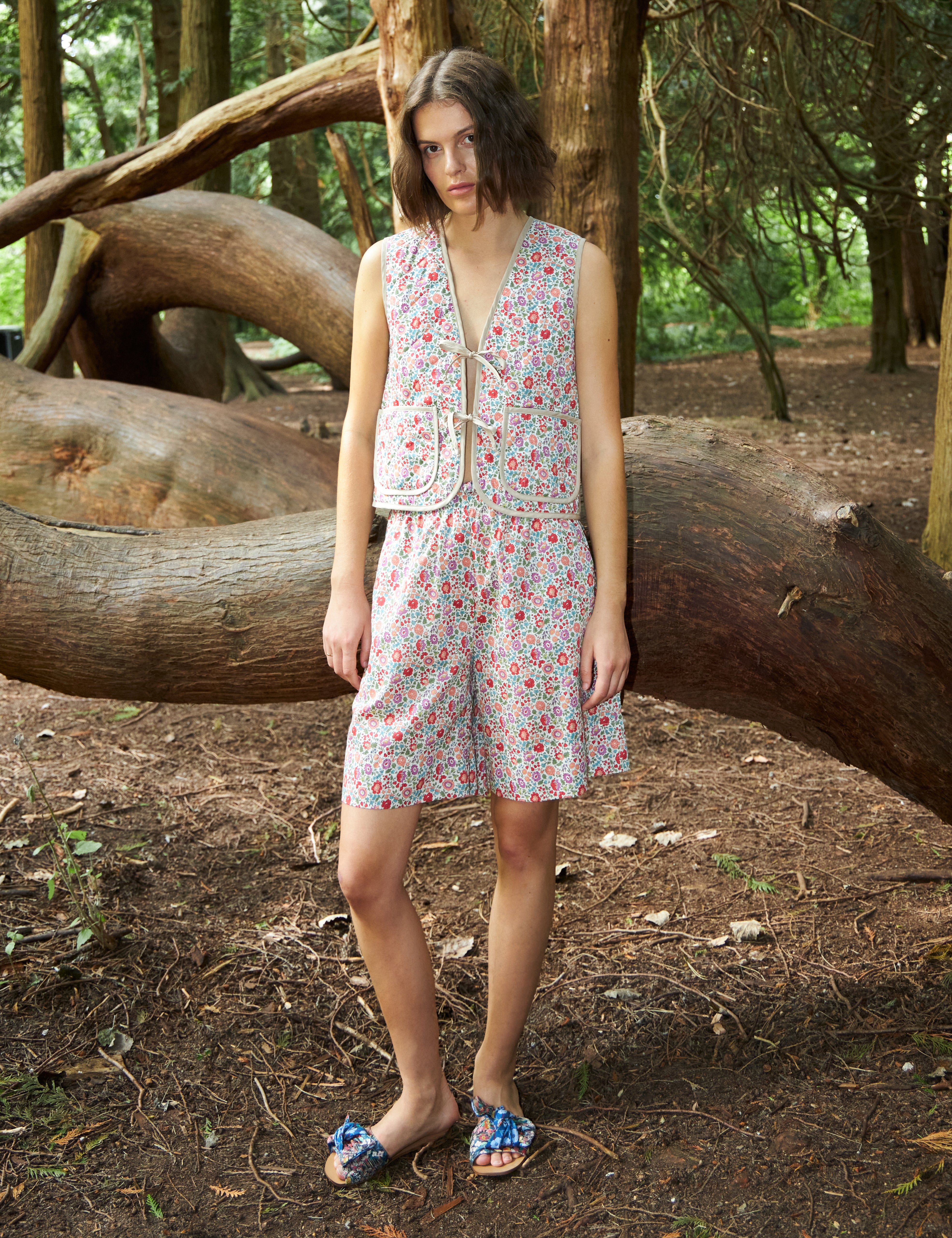 Woman in multi-colored floral print vest with pockets and matching shorts
