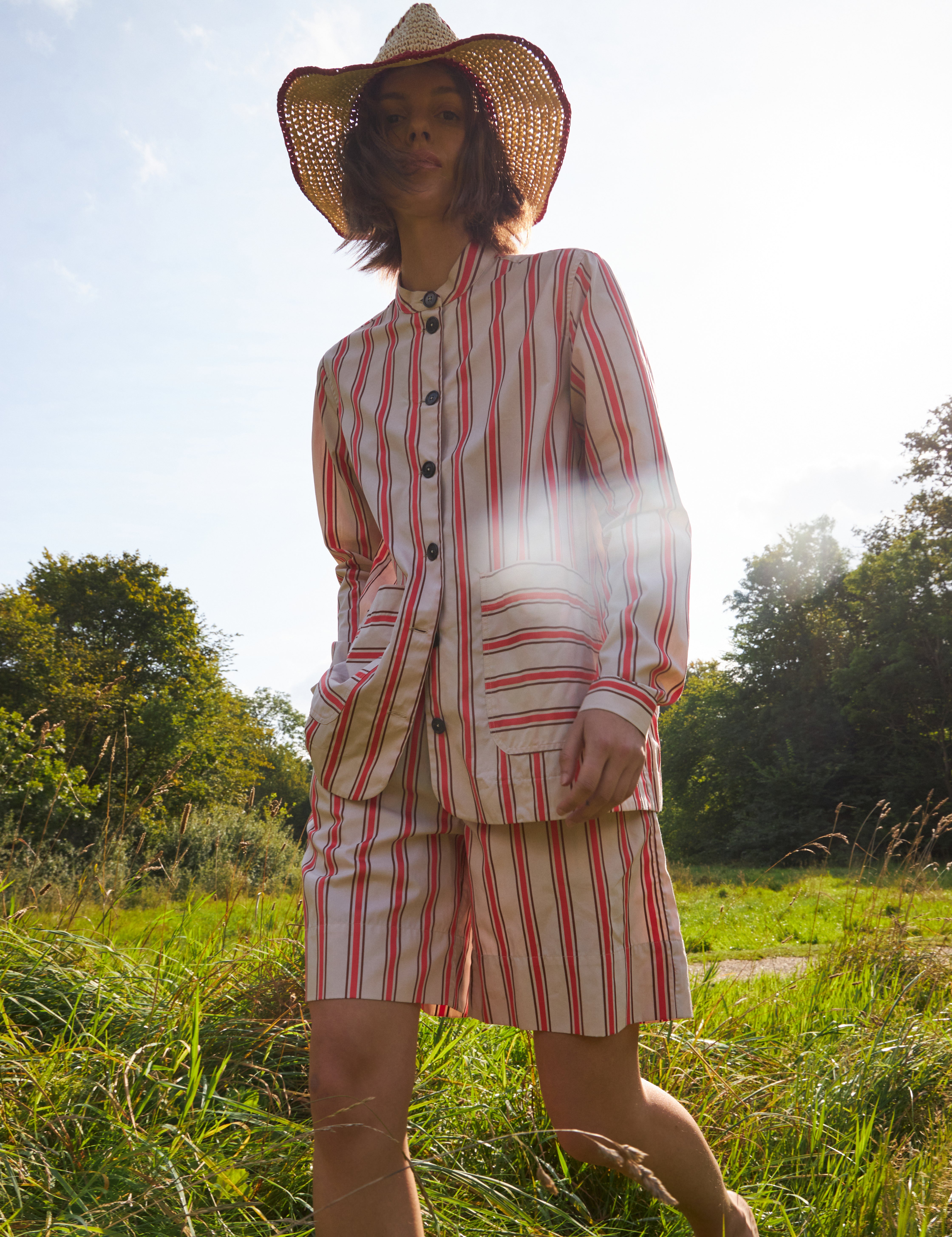 Woman in red and white striped shorts and red and white striped loose fit jacket with pockets and black buttons