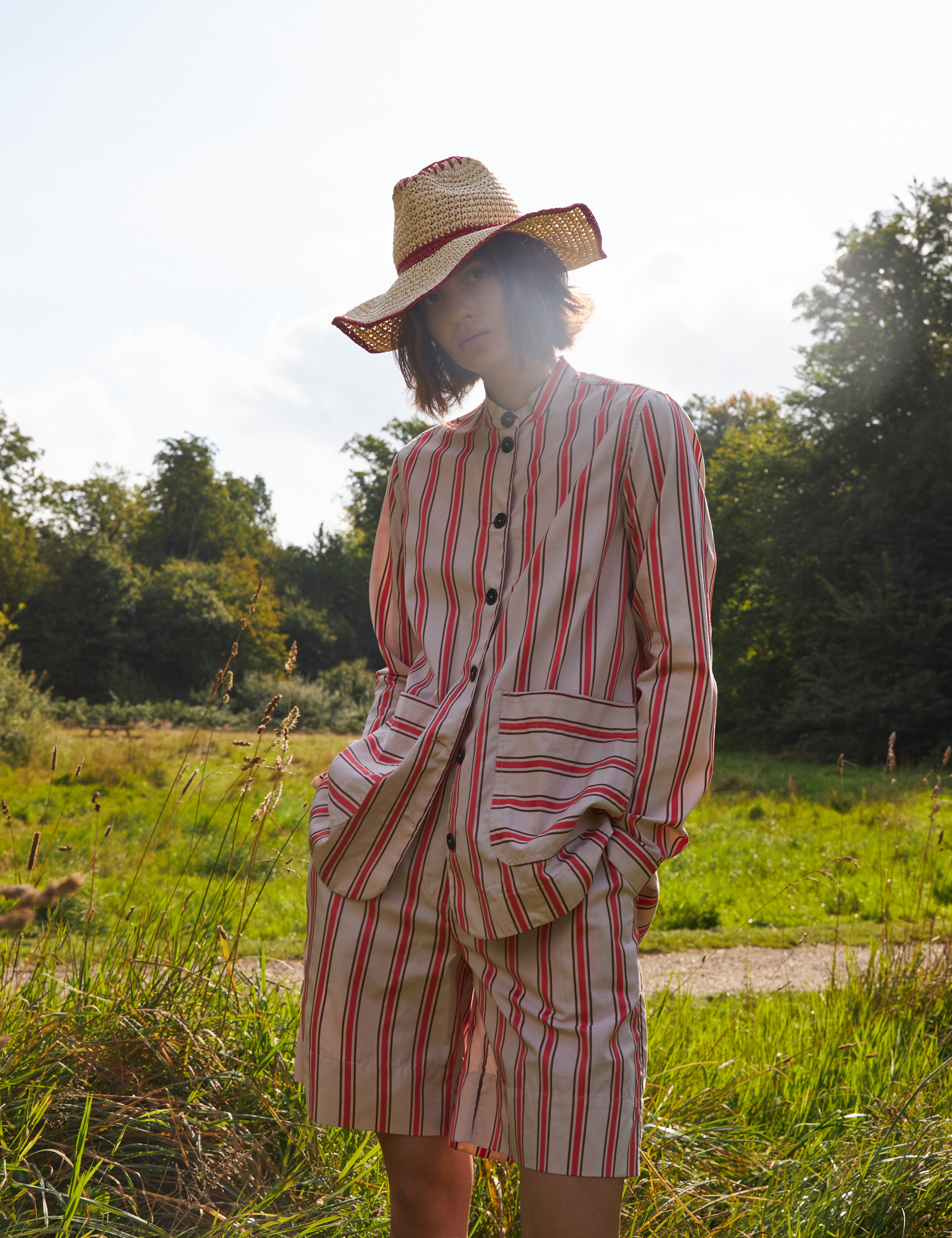 Woman in red and white striped shorts and red and white striped loose fit jacket with pockets and black buttons