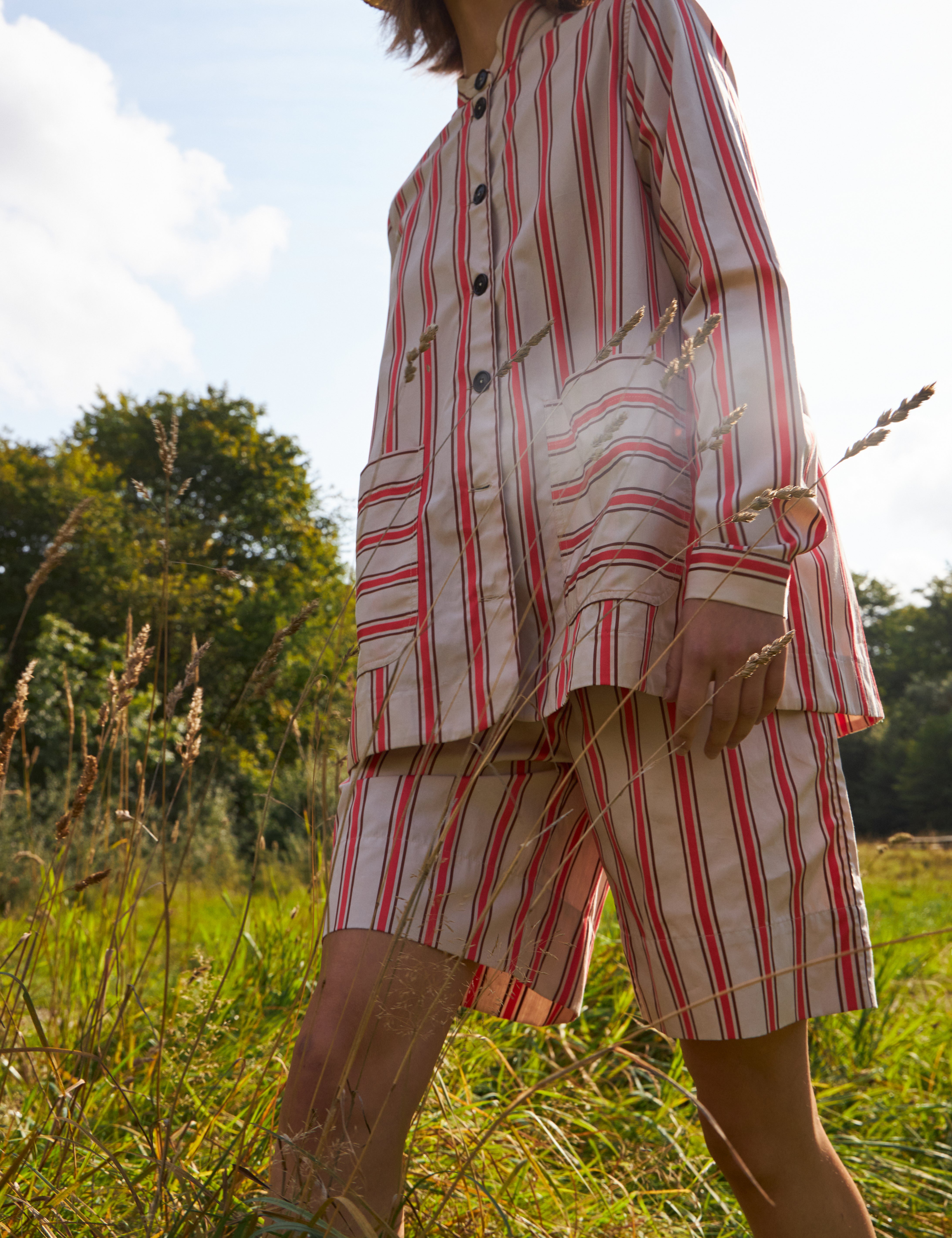Woman in red and white striped shorts and red and white striped loose fit jacket with pockets and black buttons