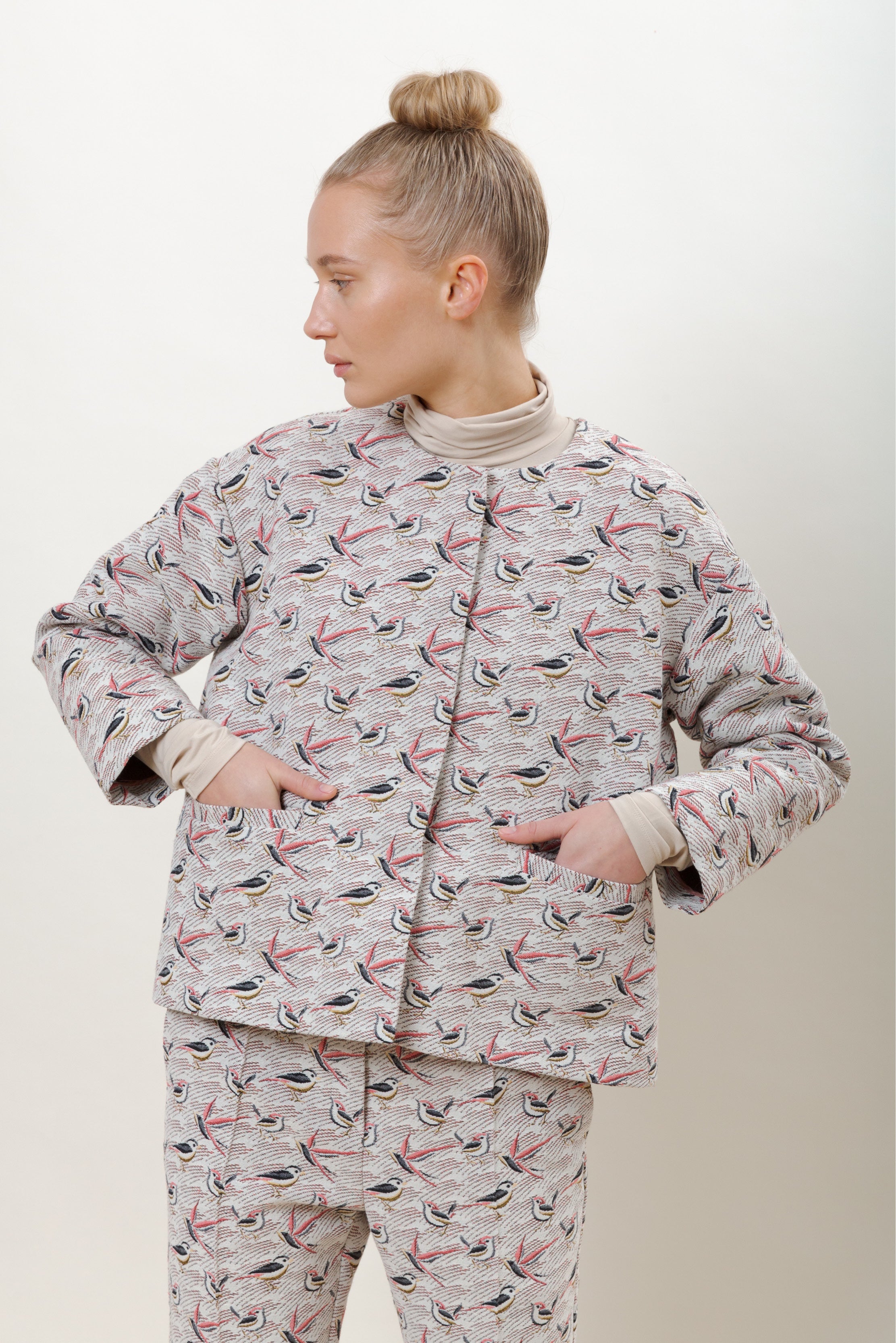 Woman in jacket and pants with bird pattern and beige roll neck
