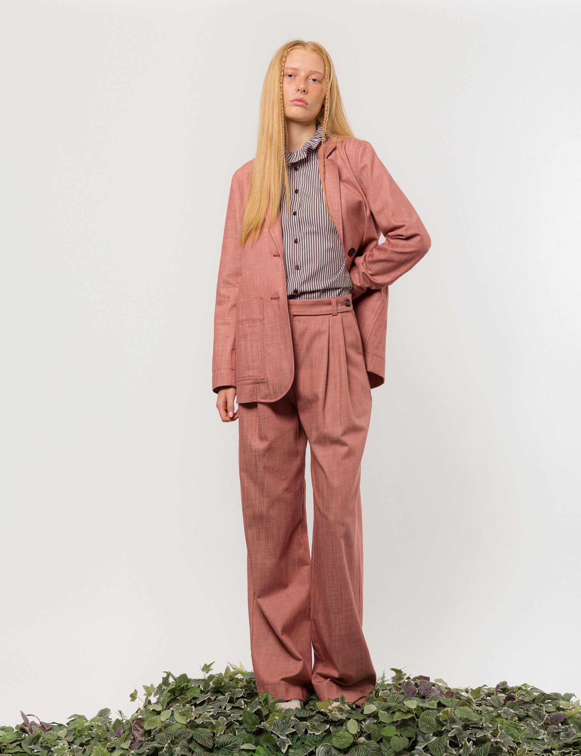 Woman in pink suit and brown and white striped shirt with ruffled collar