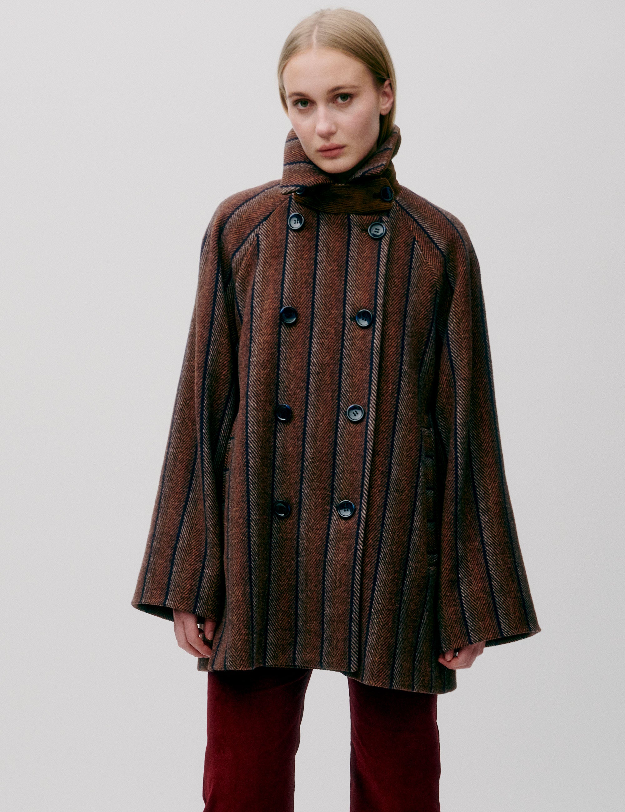 Woman wearing a brown striped wool jacket with large black buttons and red corduroy pants