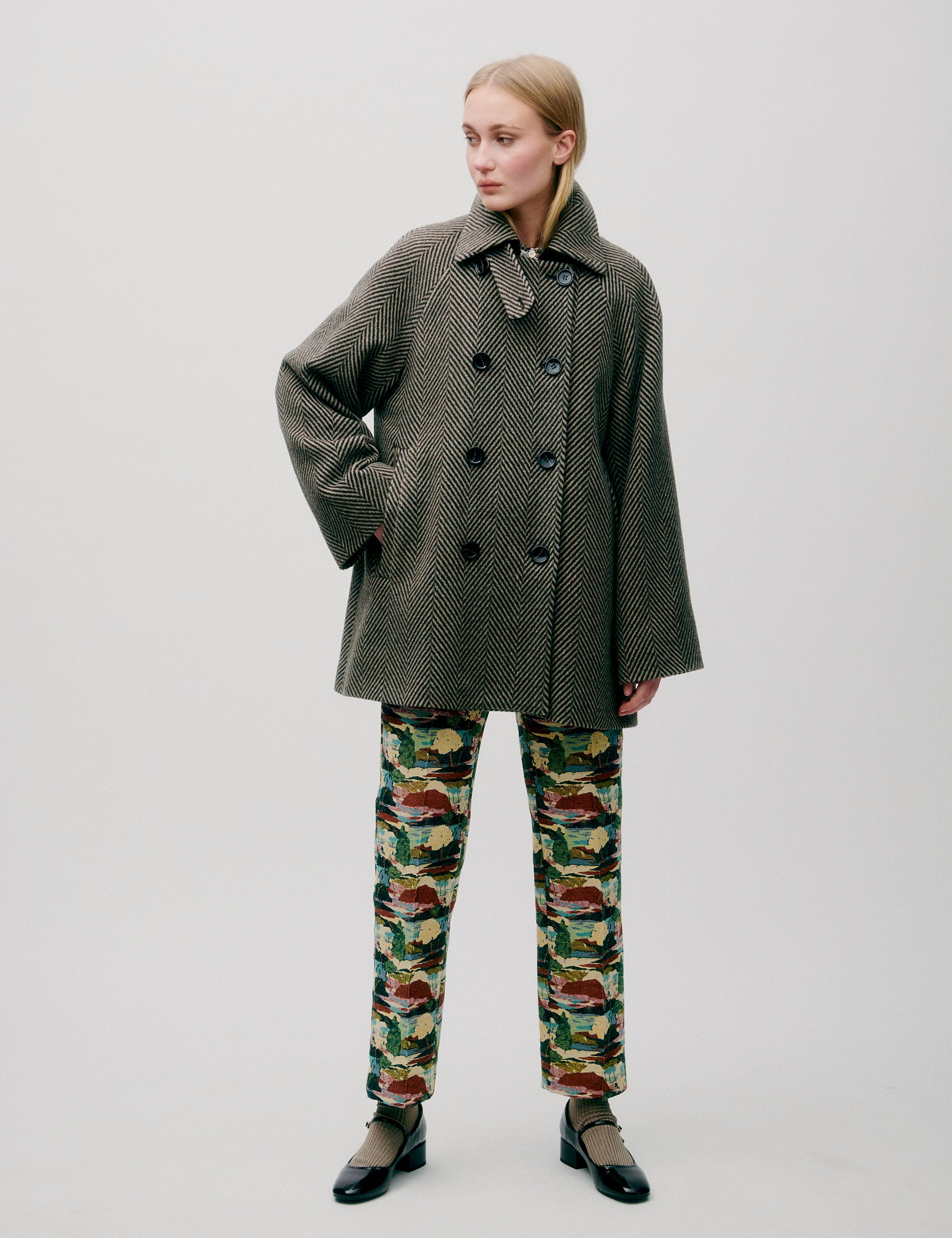 Woman in herringbone patterned green wool jacket with collar, double buttons and pockets