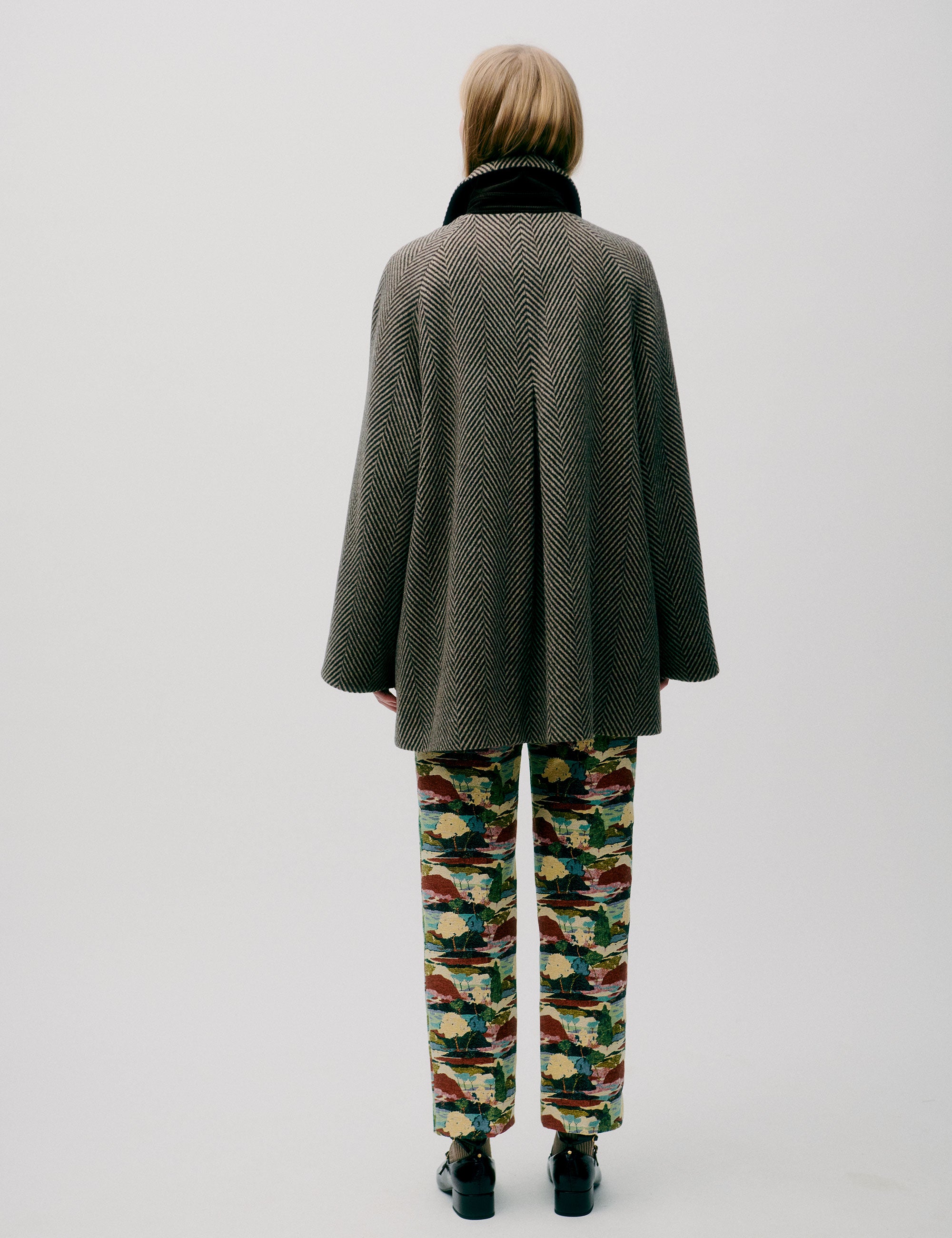 Woman in herringbone patterned green wool jacket with collar, double buttons and pockets