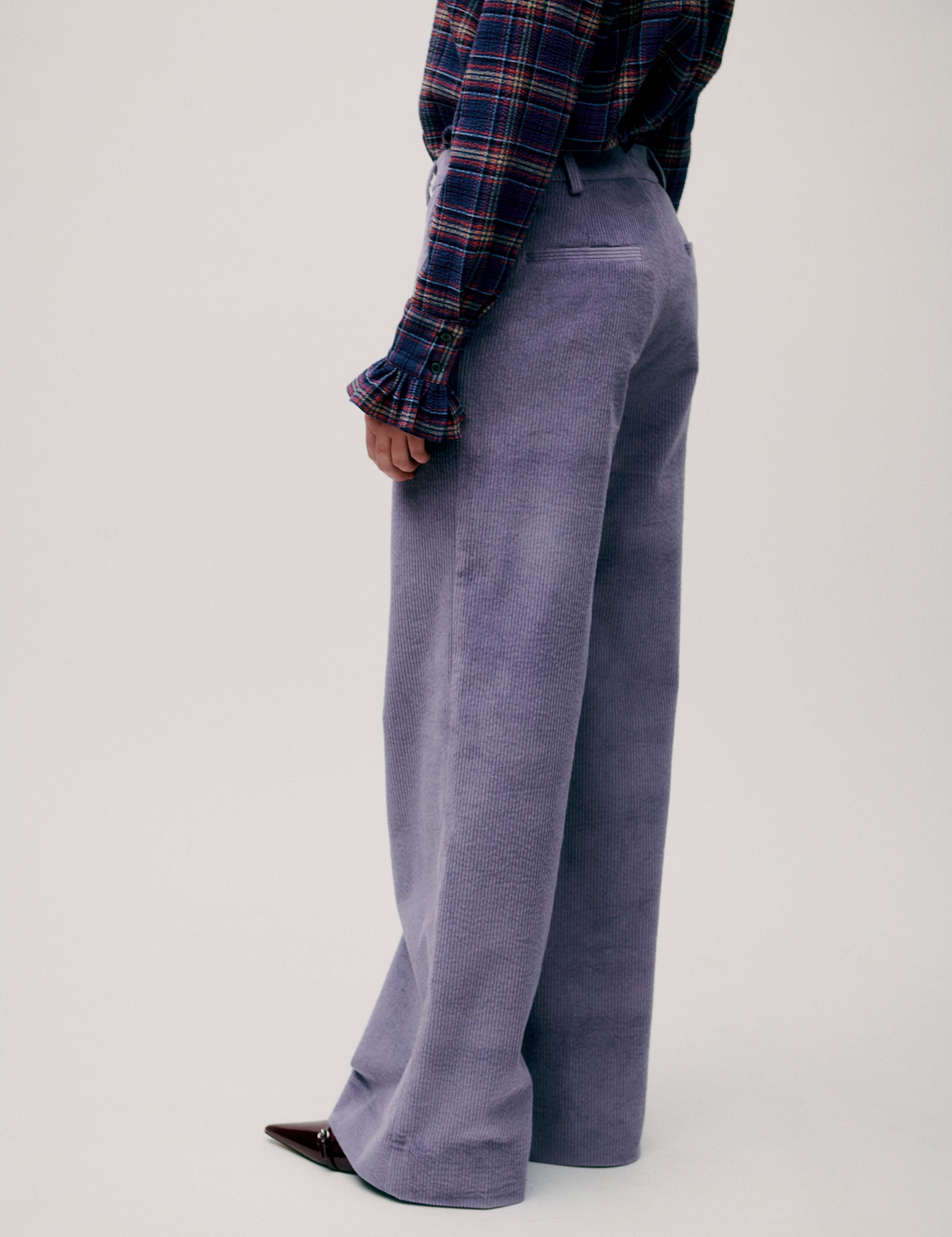 Side view of woman in purple corduroy trousers and long-sleeve shirt