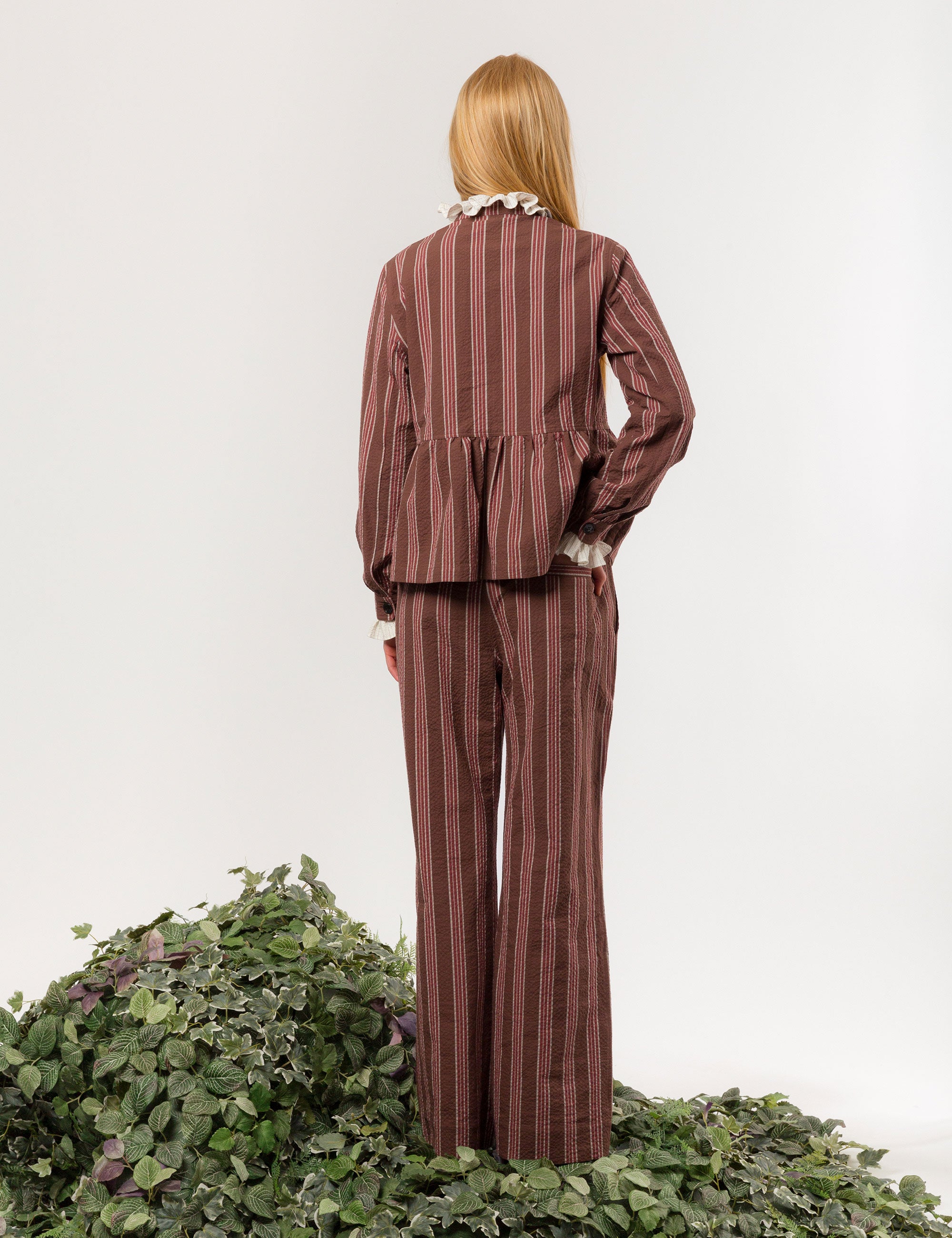 Woman in red, brown and white striped wide and relaxed cotton pants with matching jacket and frilled blouse