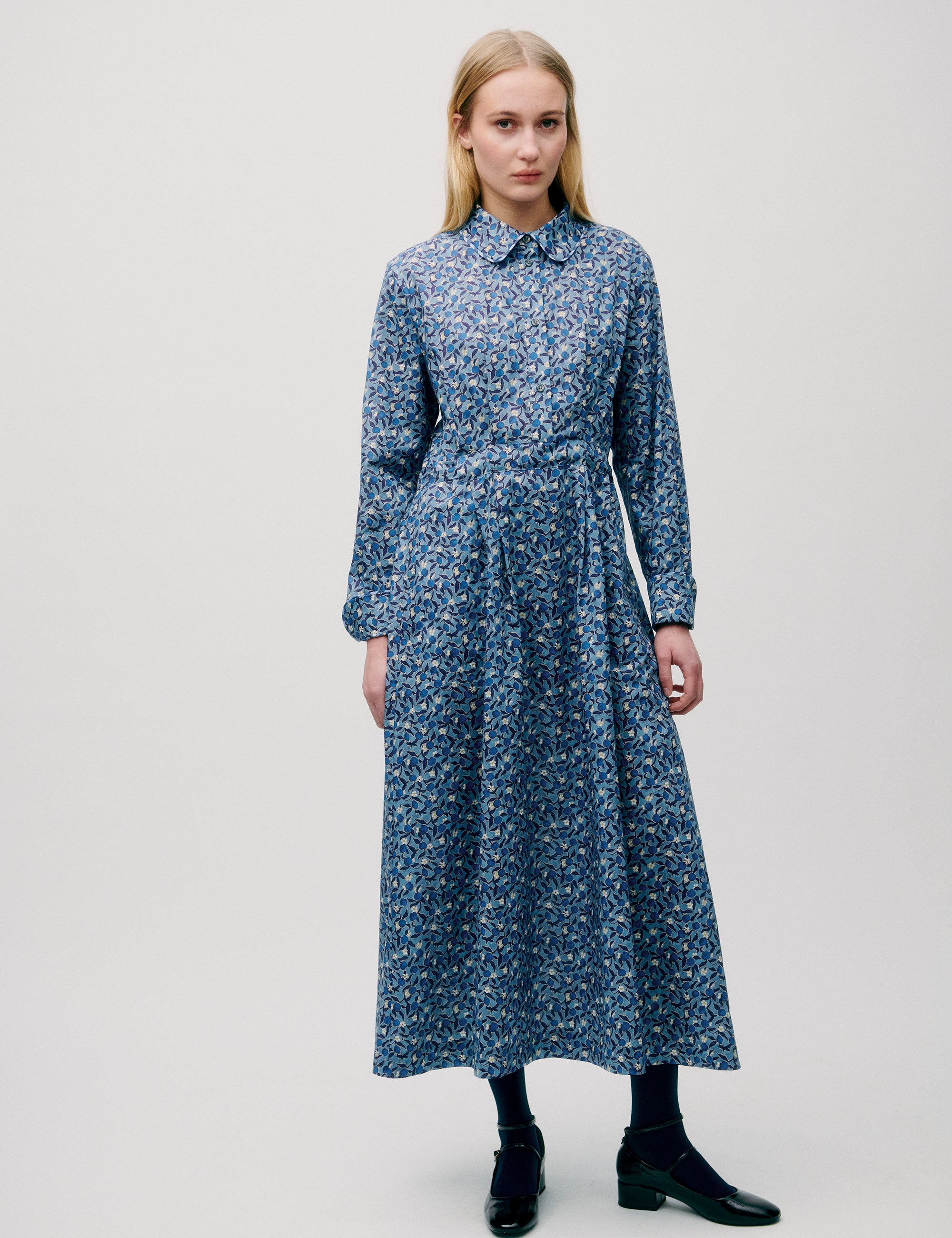 Woman in long blue flower patterned dress with long sleeves
