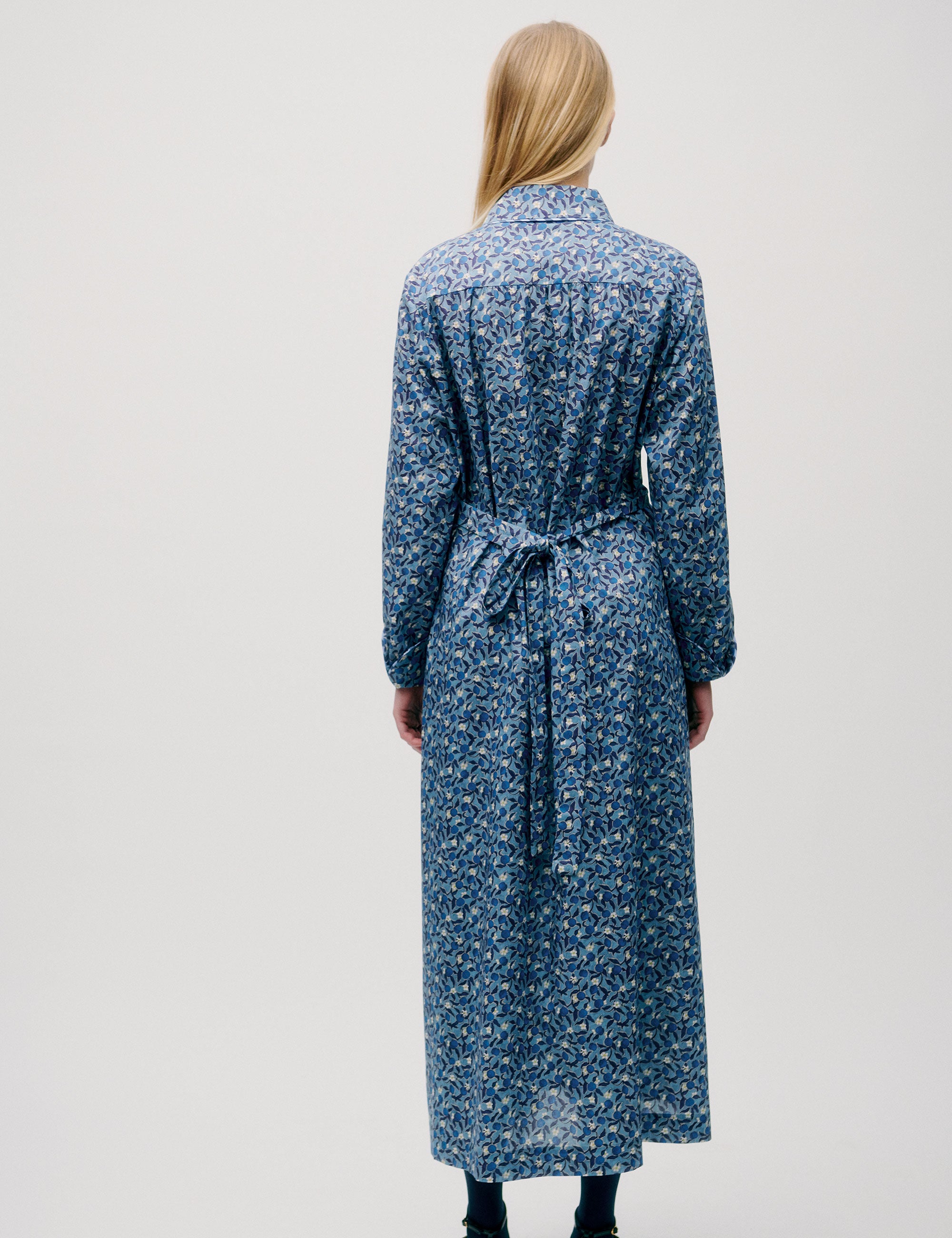 Woman in long blue flower patterned dress with long sleeves and fabric belt