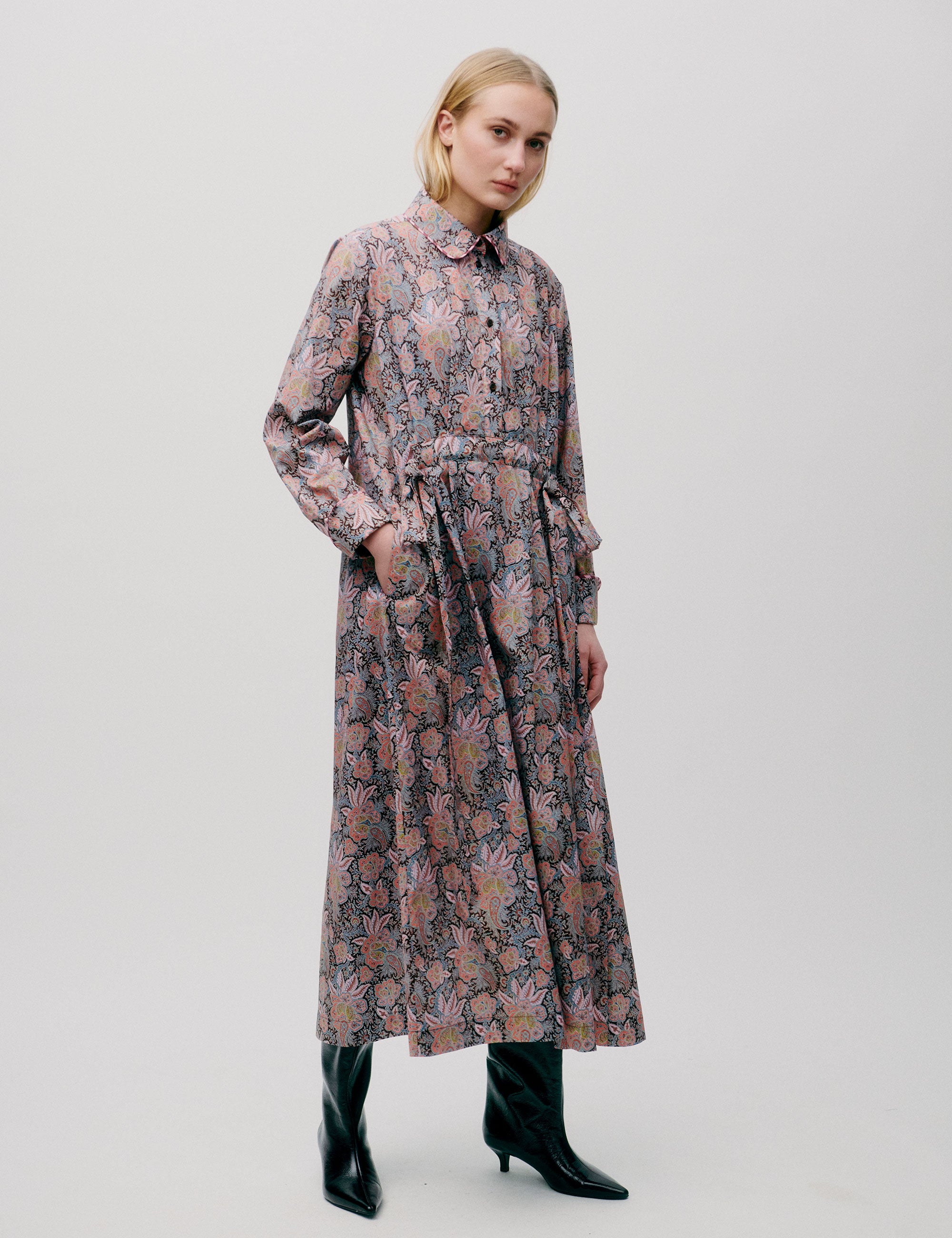 Woman in long dress with pink and blue flower paisley pattern, buttons, long sleeves and pockets