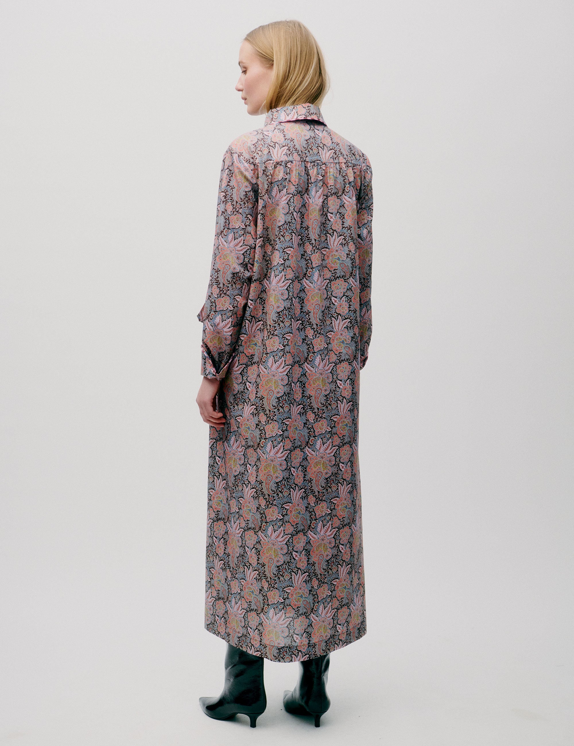 Woman in long dress with pink and blue flower paisley pattern, buttons, long sleeves and pockets