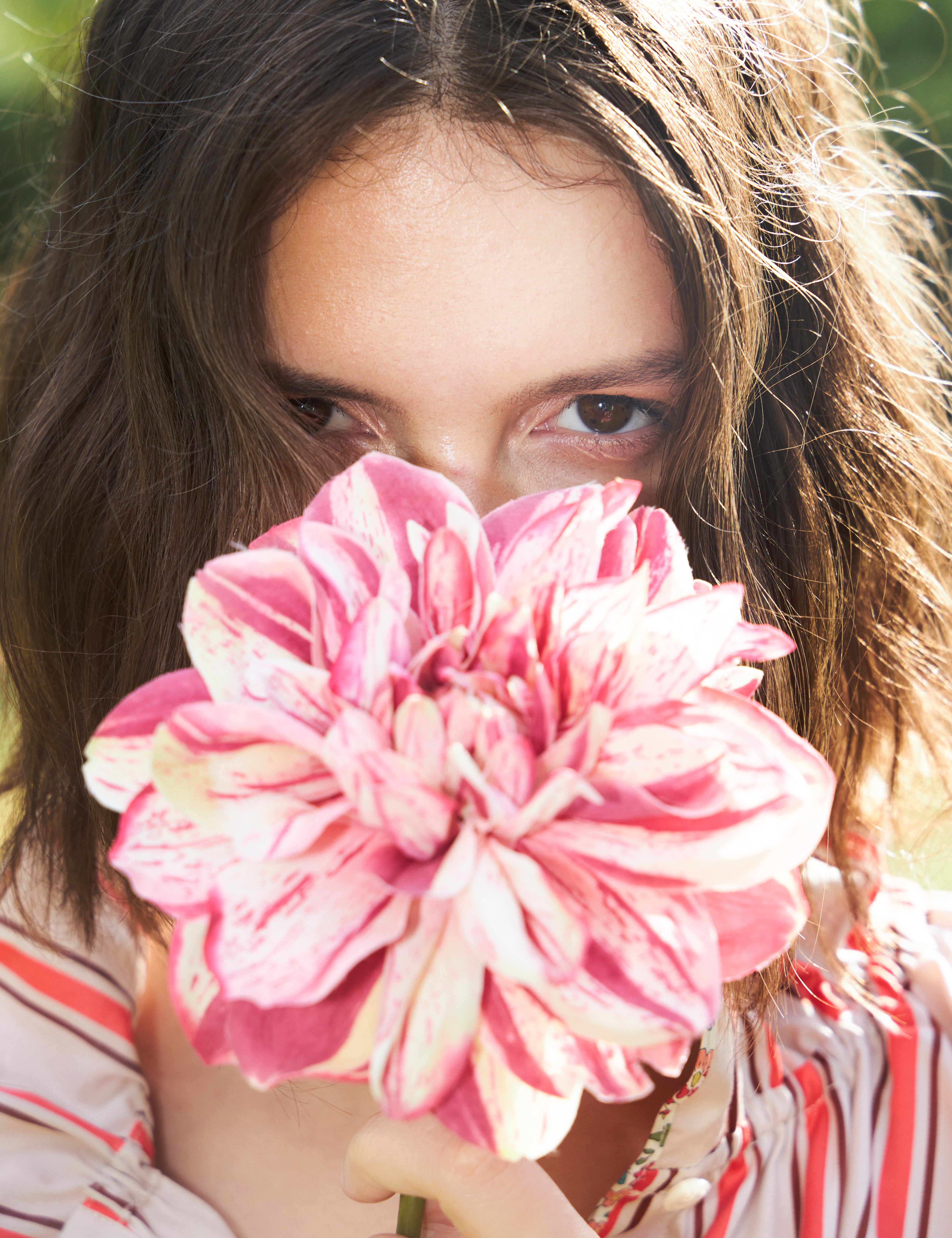 Woman in red and white striped summer dress holding a red and white flower