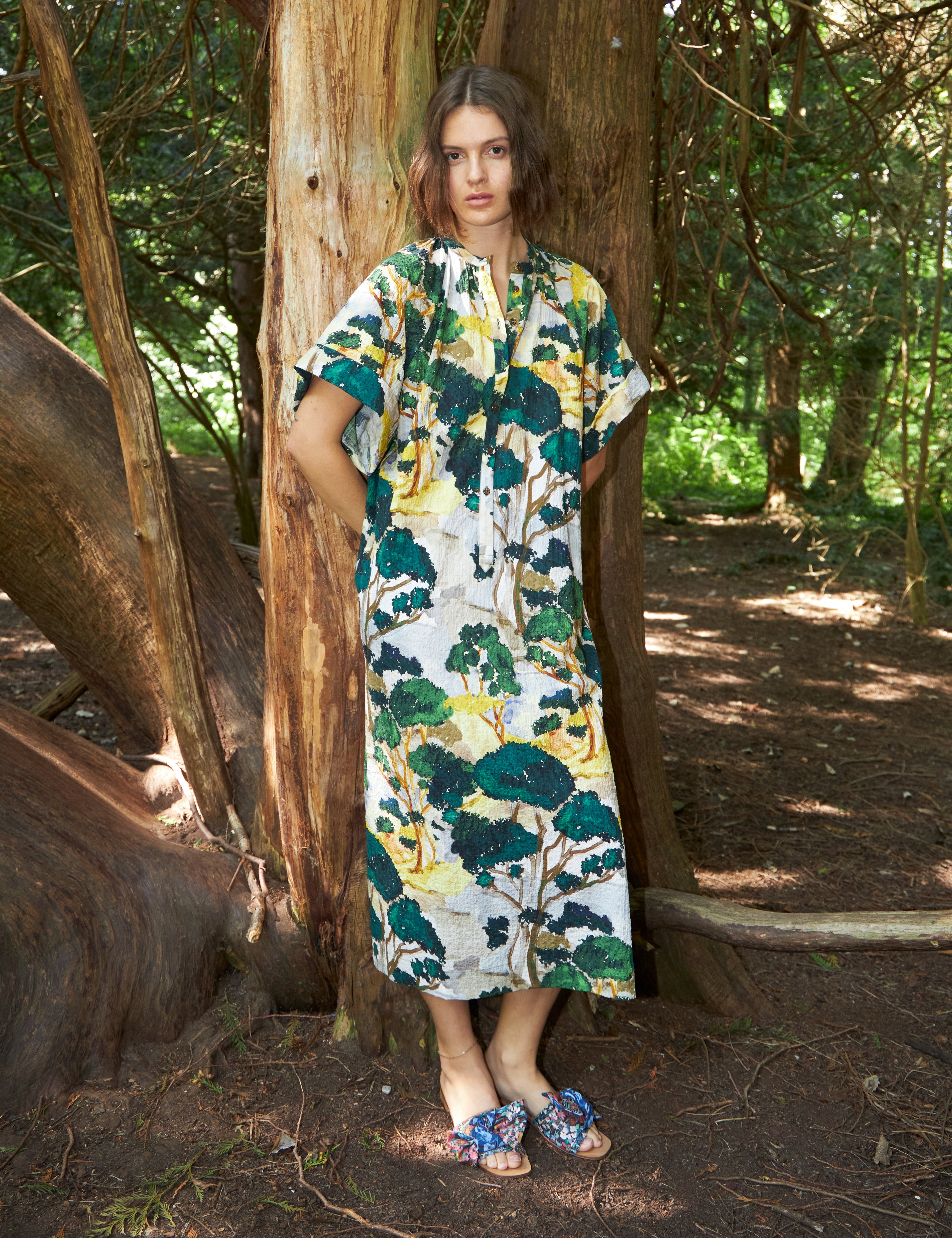 Woman in green white and yellow kimono dress with short sleves and buttons and sandals with blue floral print bows