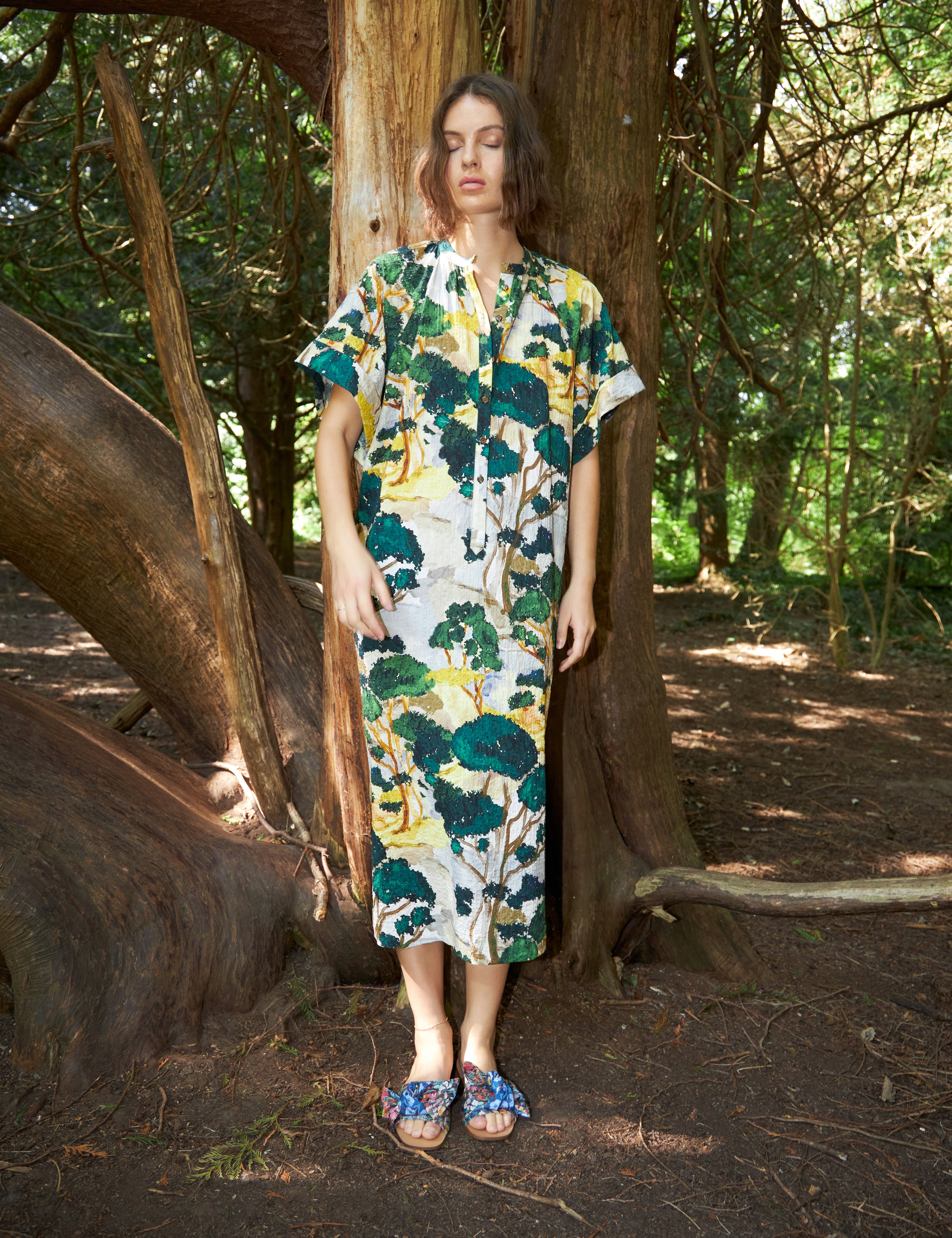 Woman in green white and yellow kimono dress with short sleves and buttons and sandals with blue floral print bows