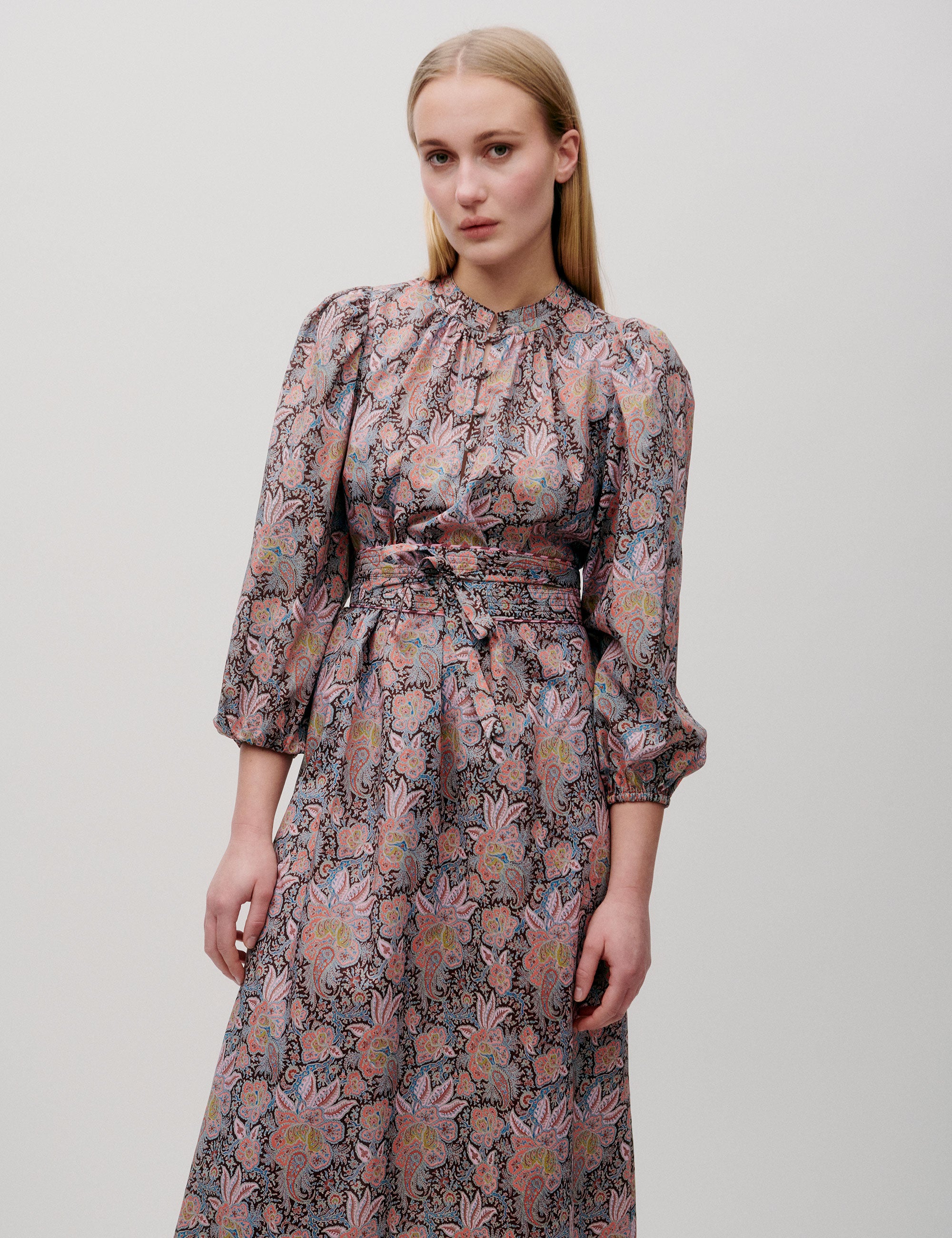 Front view of pink paisley-patterned dress with tie waist and full sleeves
