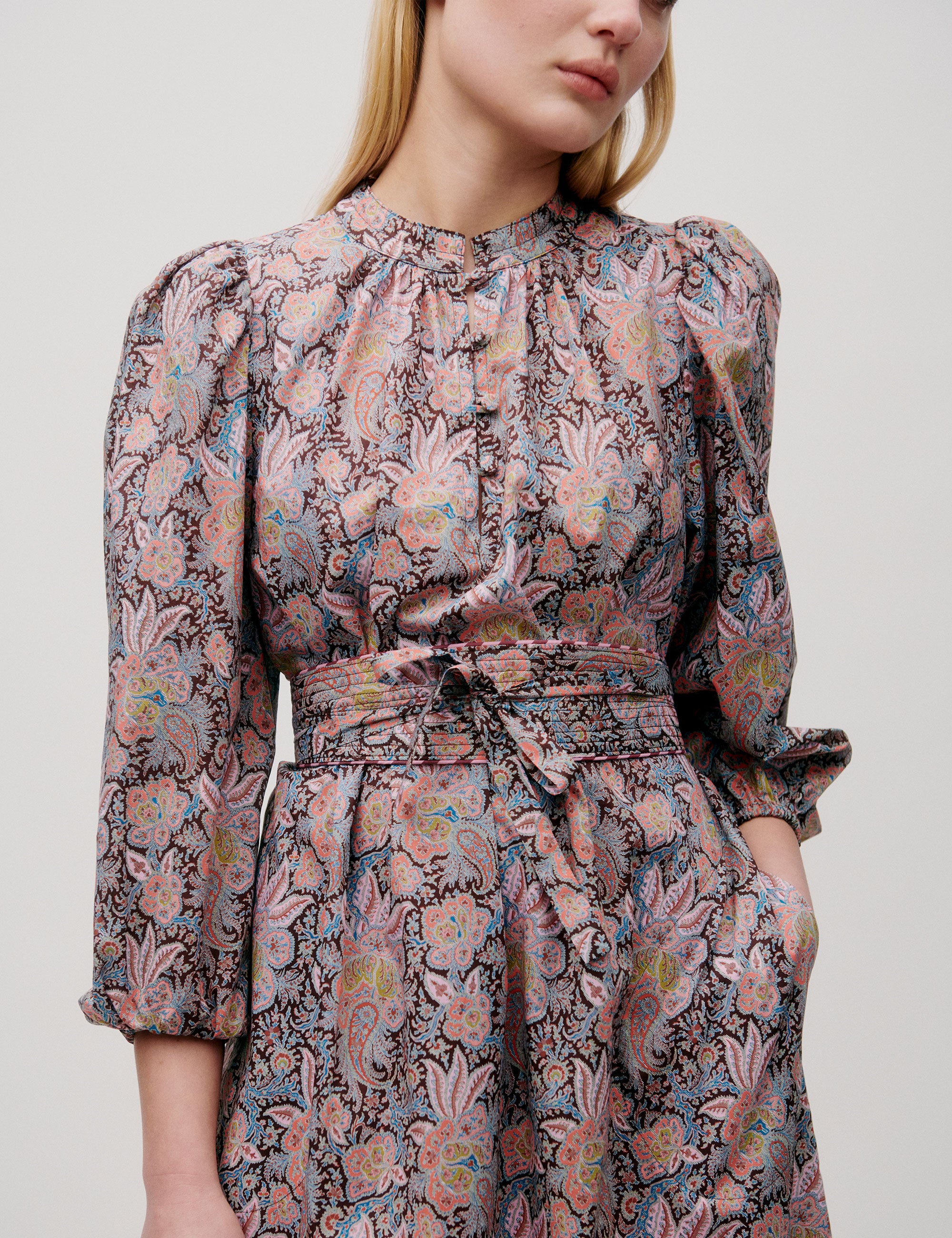 Front view of pink paisley-patterned dress with tie waist and full sleeves