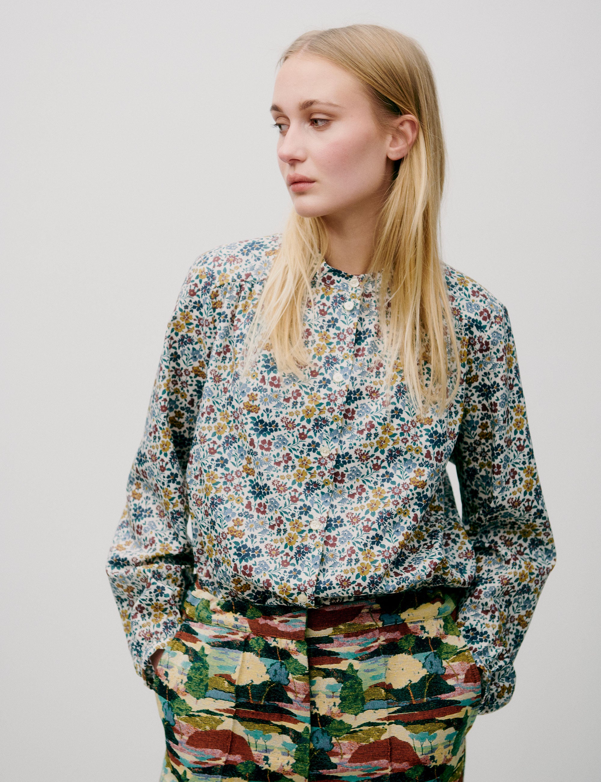Woman in blue yellow and red floral patterned shirt with buttons and forest print pants
