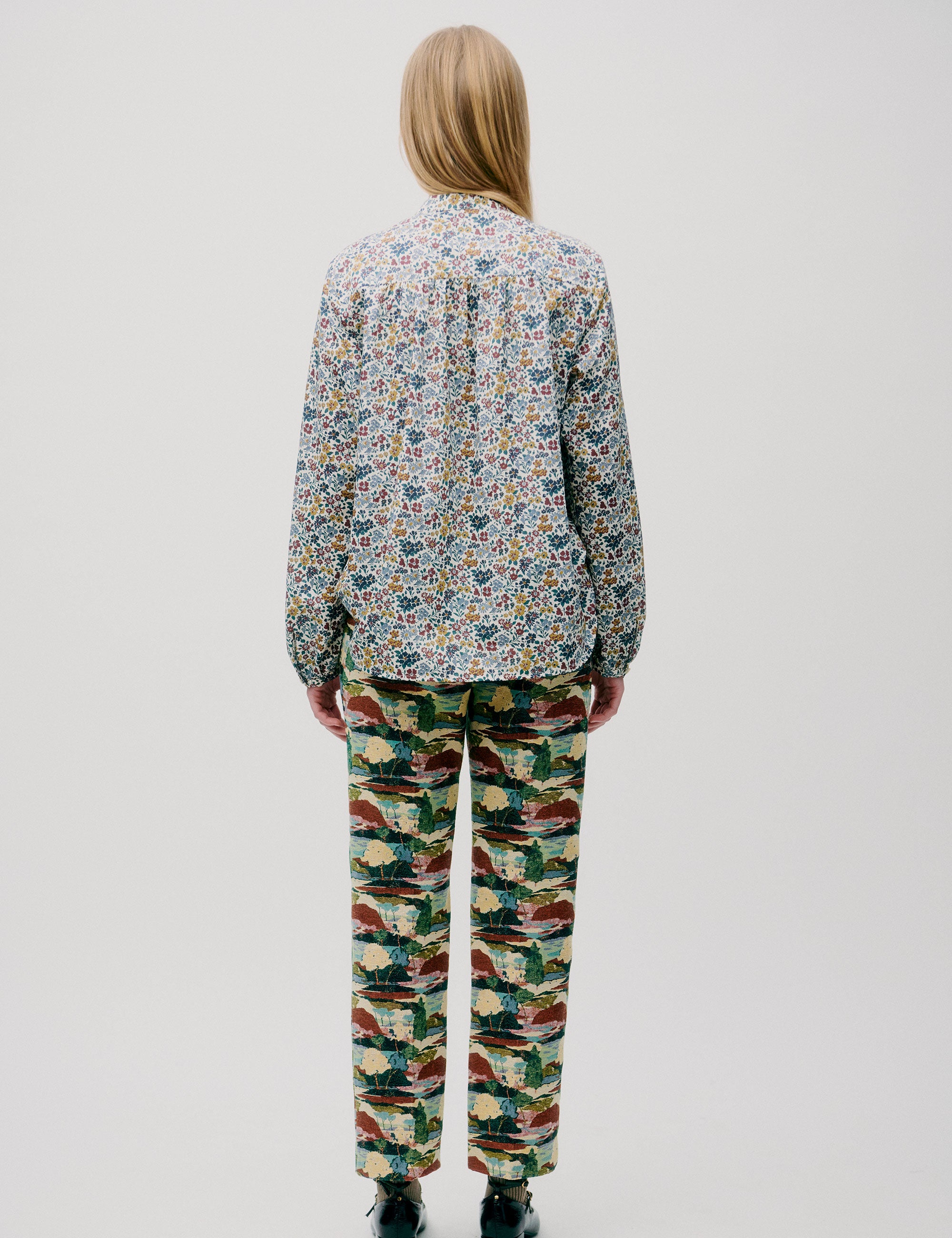 Woman in blue yellow and red floral patterned shirt with buttons and forest print pants