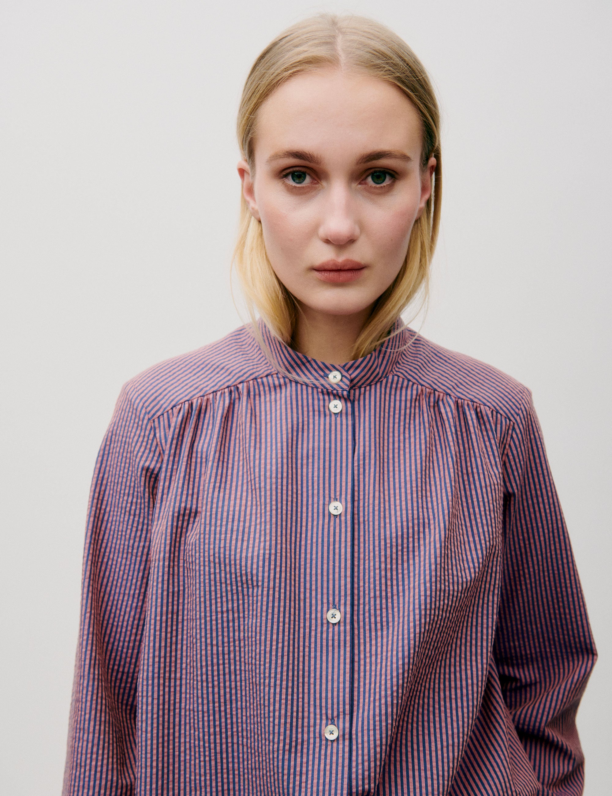 Woman in long sleeved pink striped shirt with white buttons