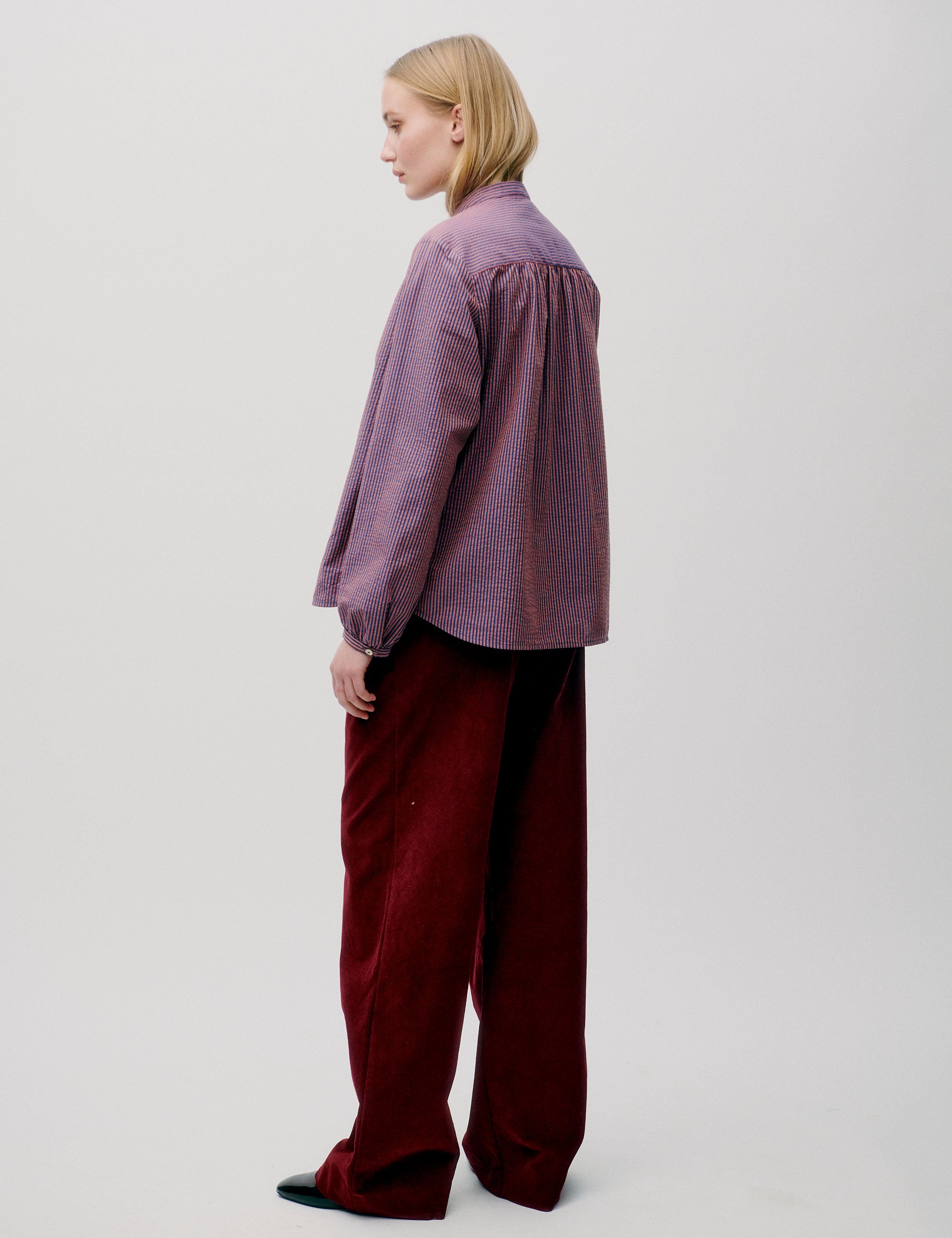 Woman in long sleeved pink striped shirt and red trousers