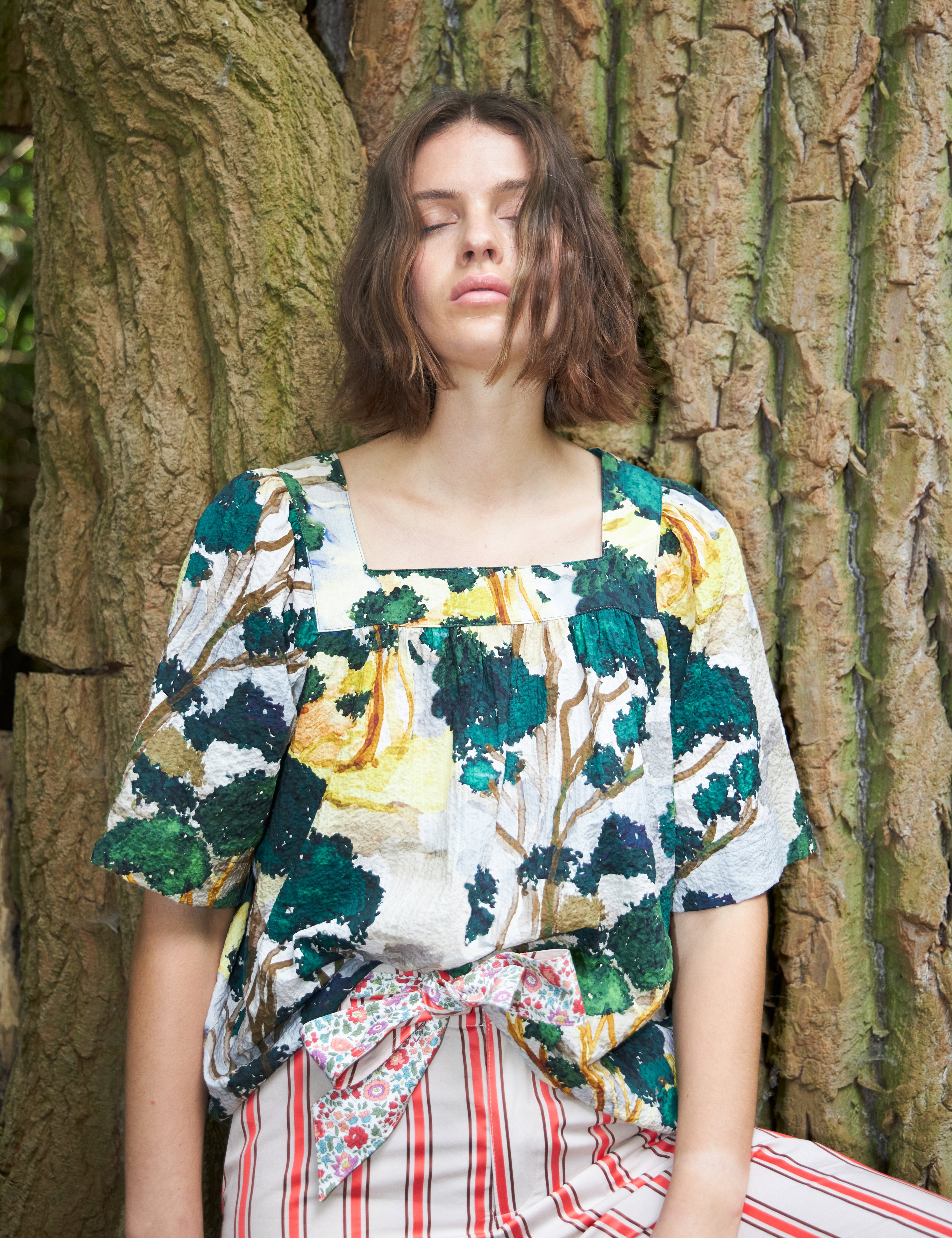Woman in red and white striped pants and loose fit blouse with short sleeves in green yellow and white artistic patterned cotton