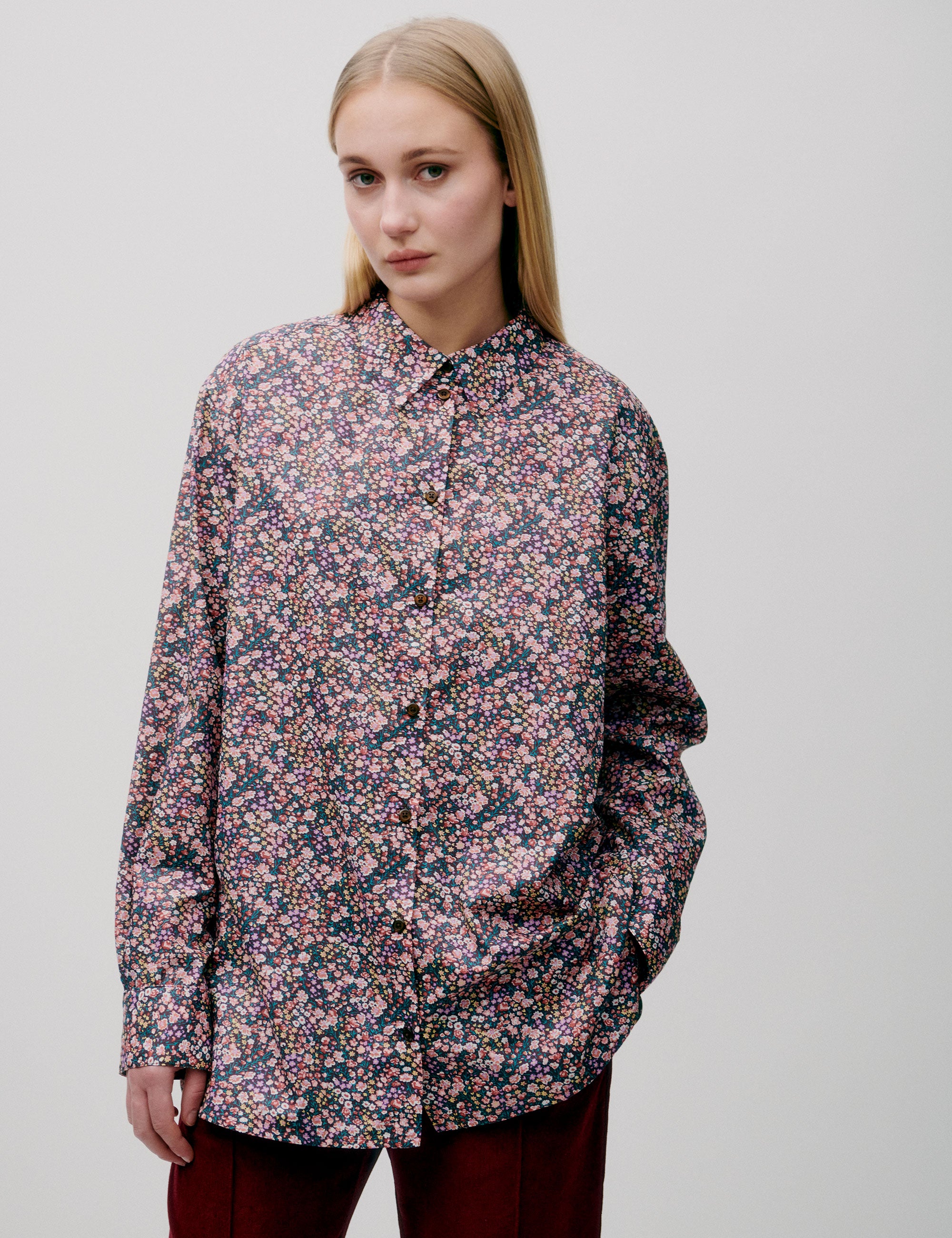 Woman in straight pink and blue small flower patterned shirt with long sleeves