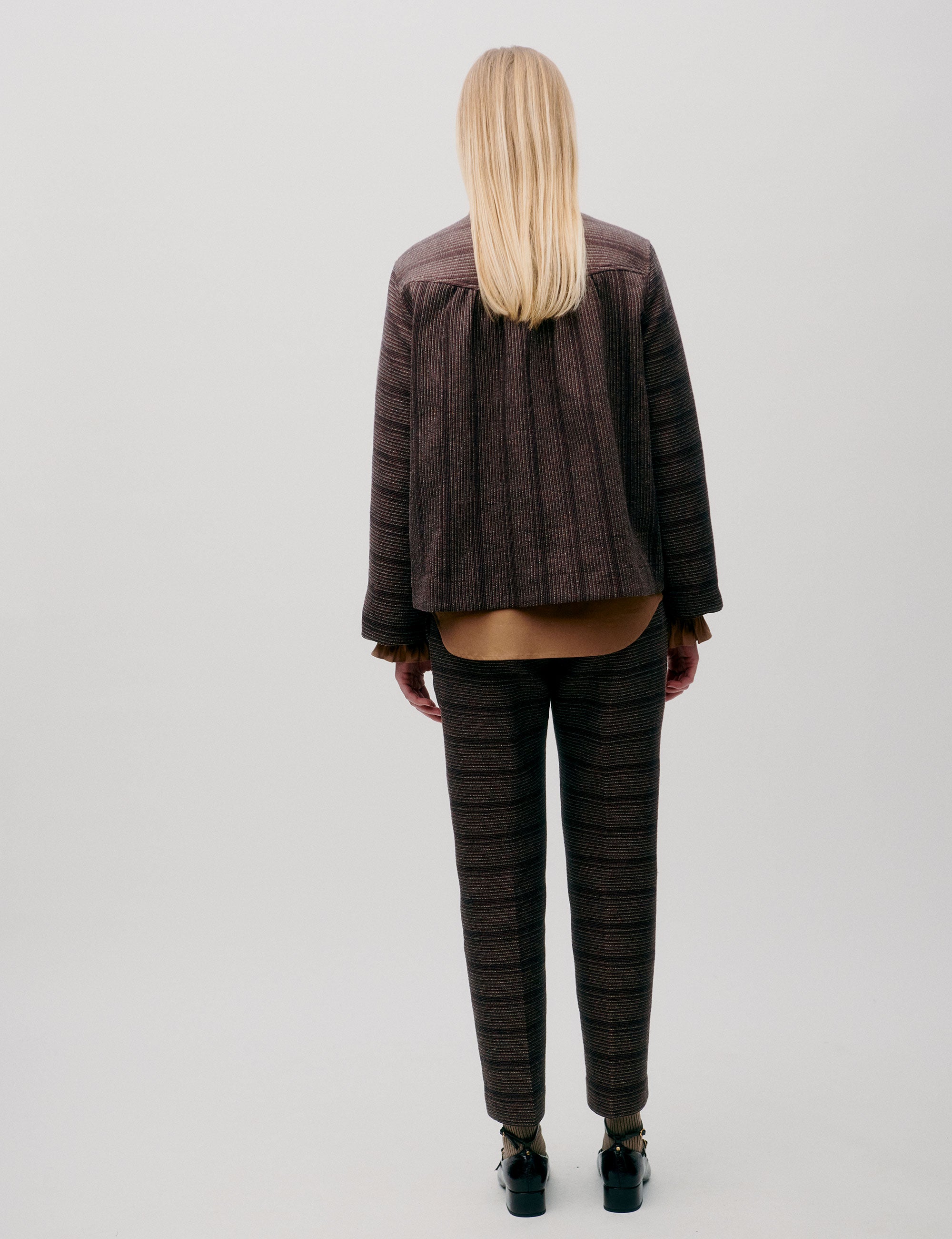 Back view of woman in brown wool jacket and matching patterned trousers