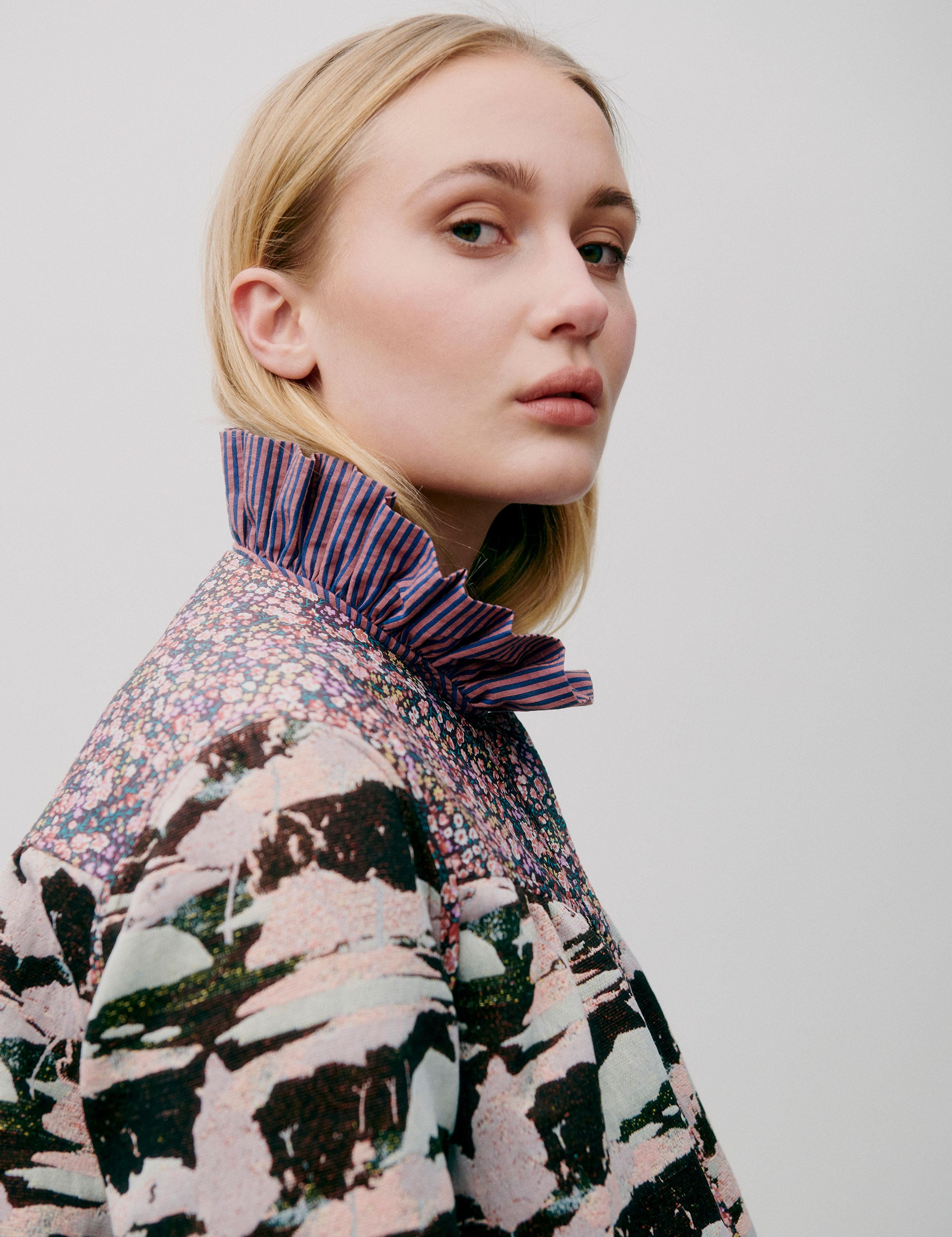 Woman pink striped shirt with frills and quilted jacket with floral and artistic print