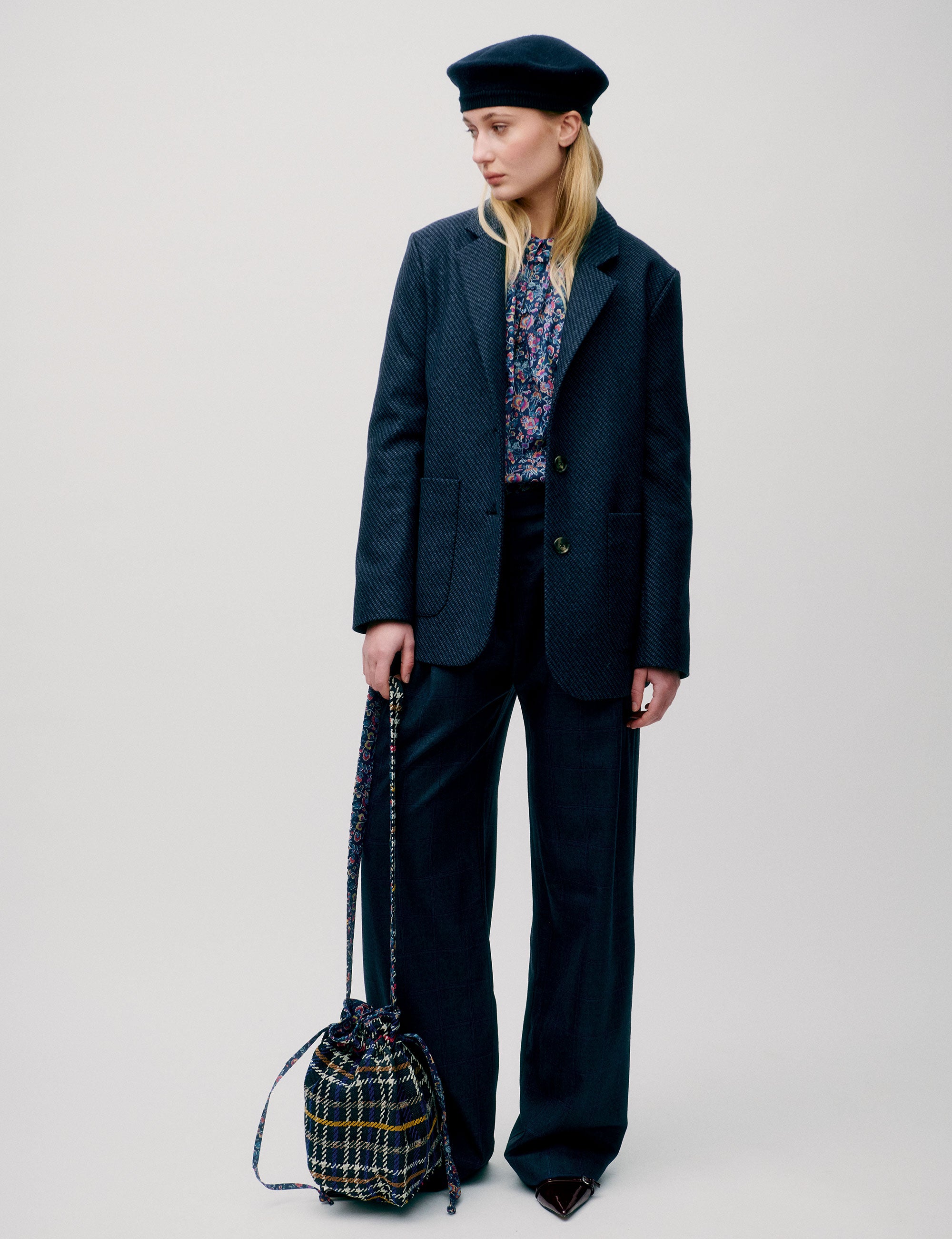 Woman in dark blue wide wool pants, flower patterned blue and pink shirt, dark blue wool jacket with pockets and blue beret