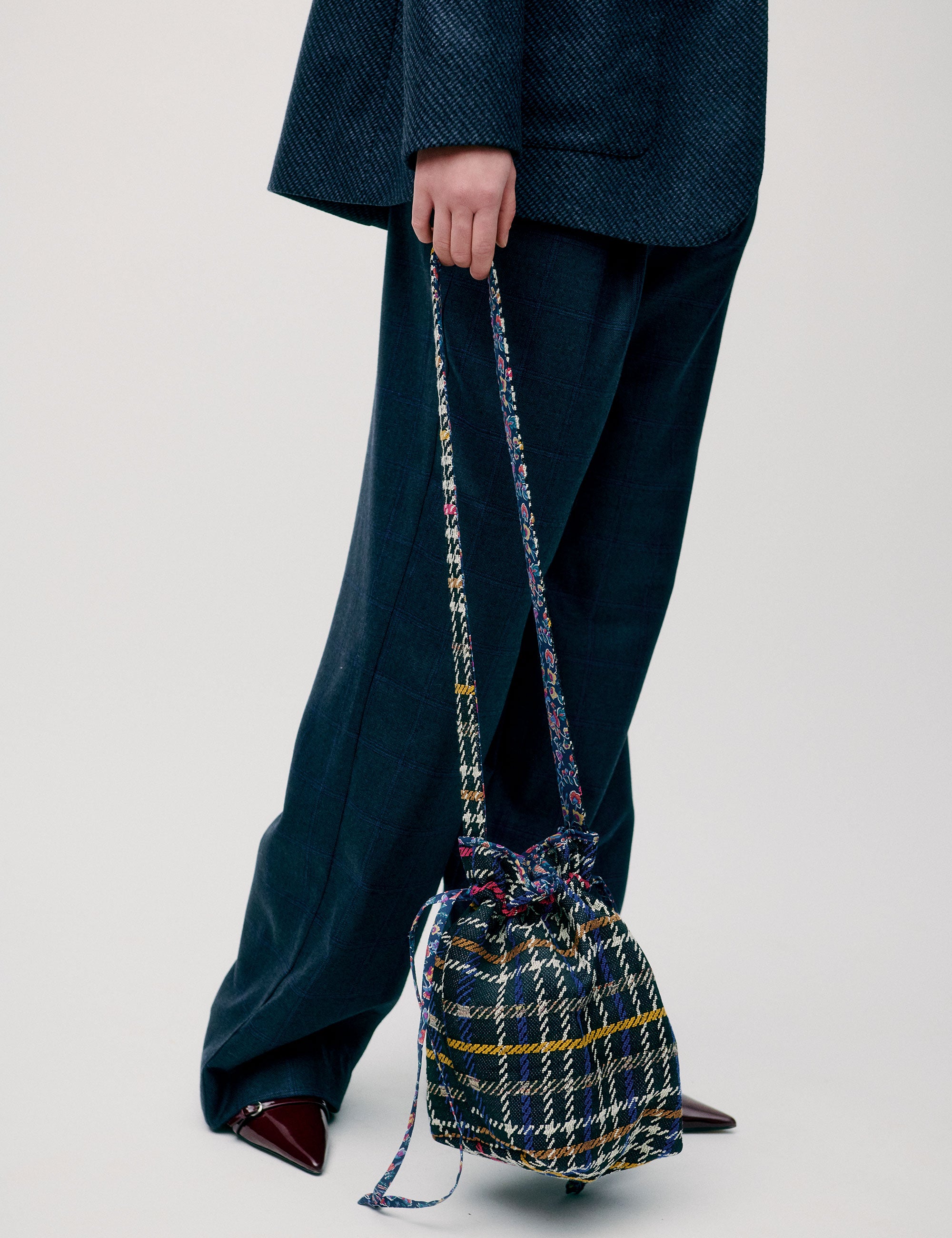 Woman in blue wool costume carrying a small cotton bag with checked pattern