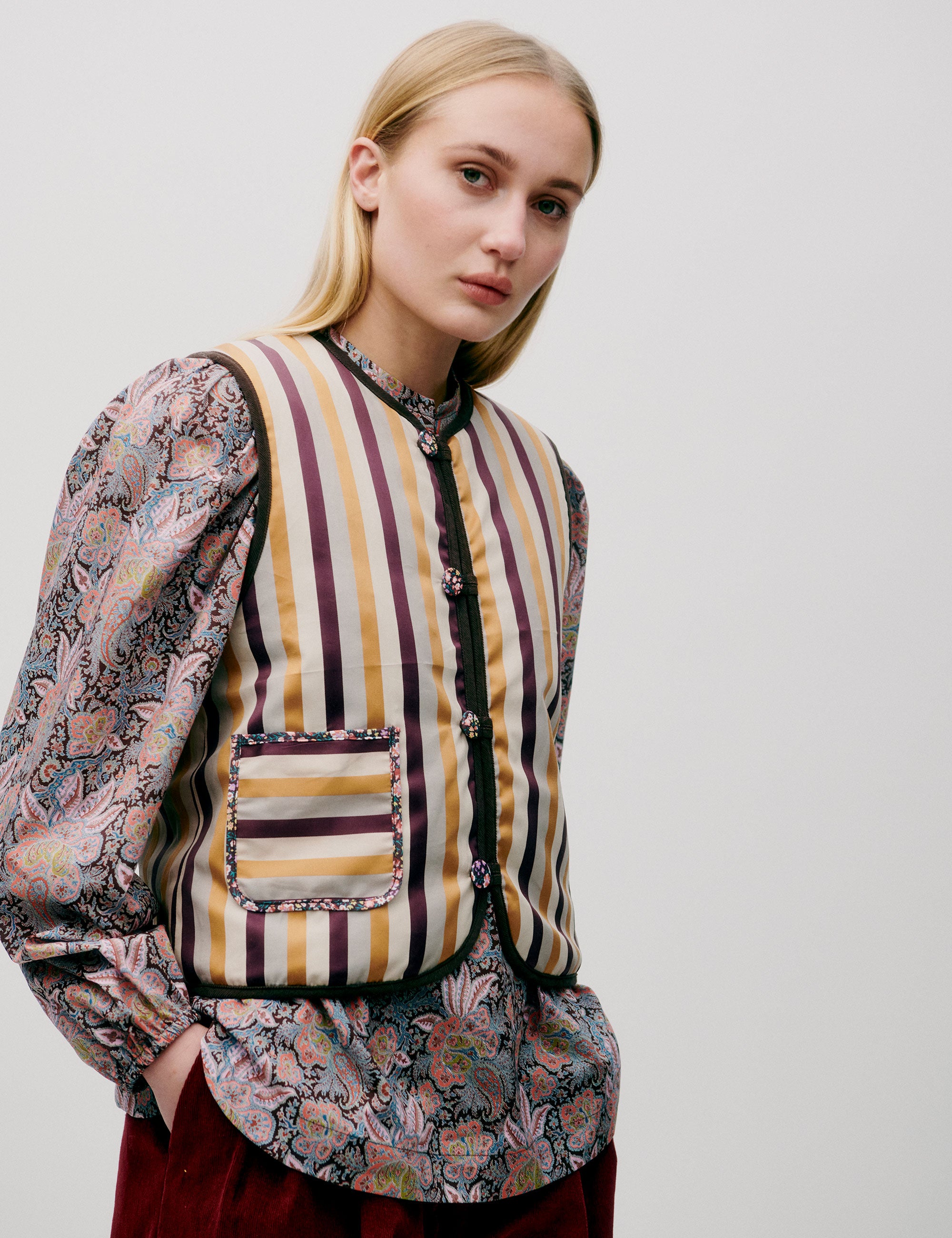 Woman in red trousers, flower paisley patternedblouse and yellow white and red striped vest