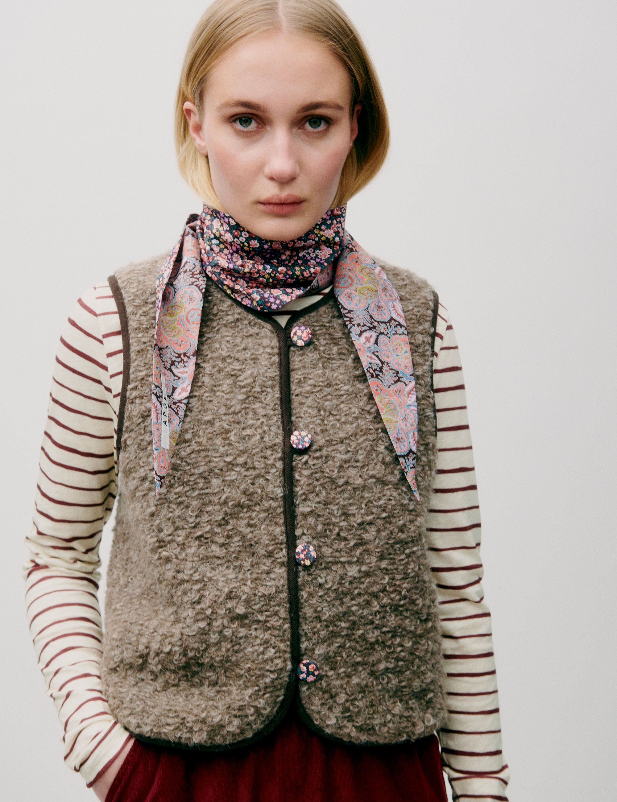 Woman in red corduroy skirt, striped long sleeved t-shirt and wool vest with buttons and lining