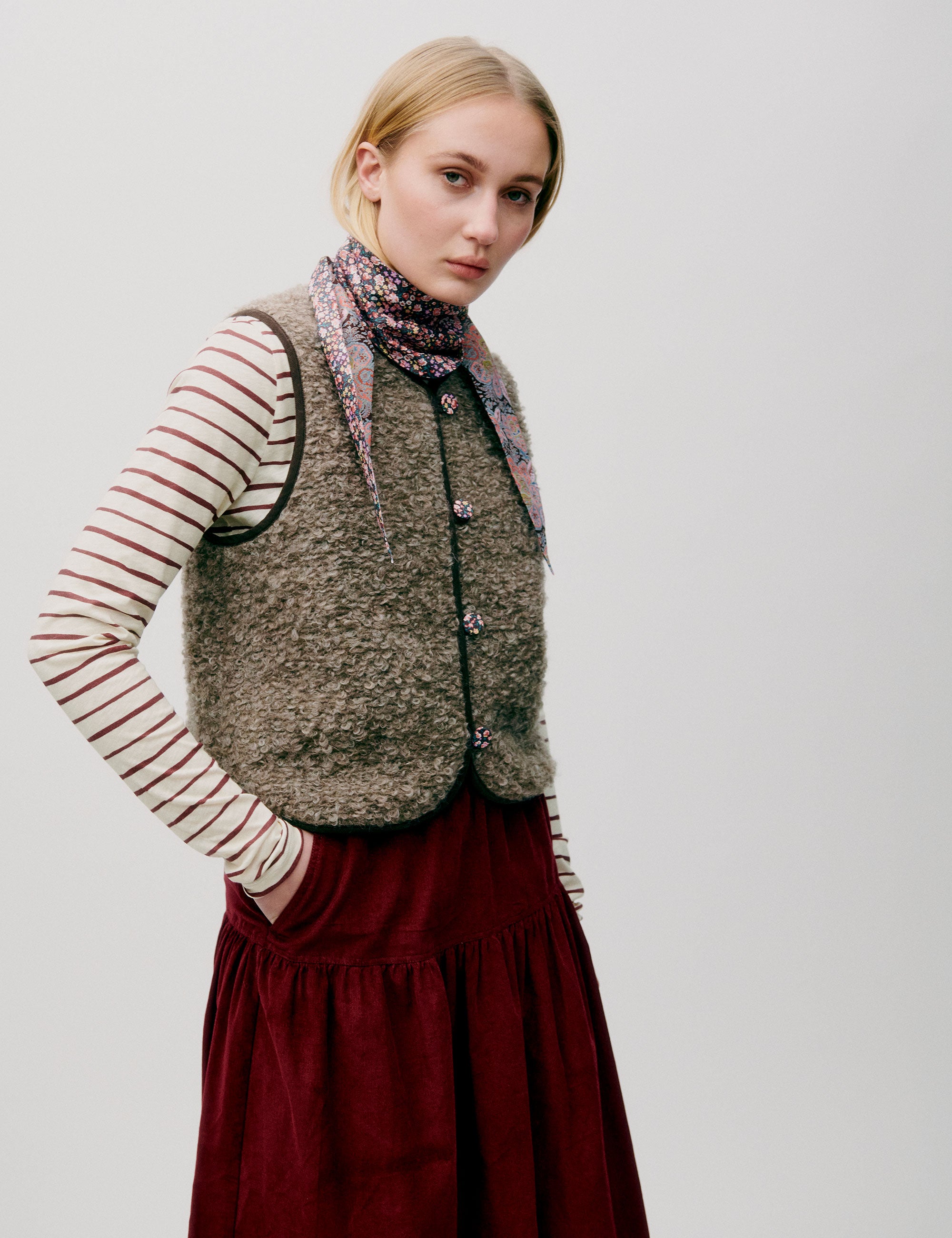 Woman in red corduroy skirt, striped long sleeved t-shirt and wool vest with buttons and lining