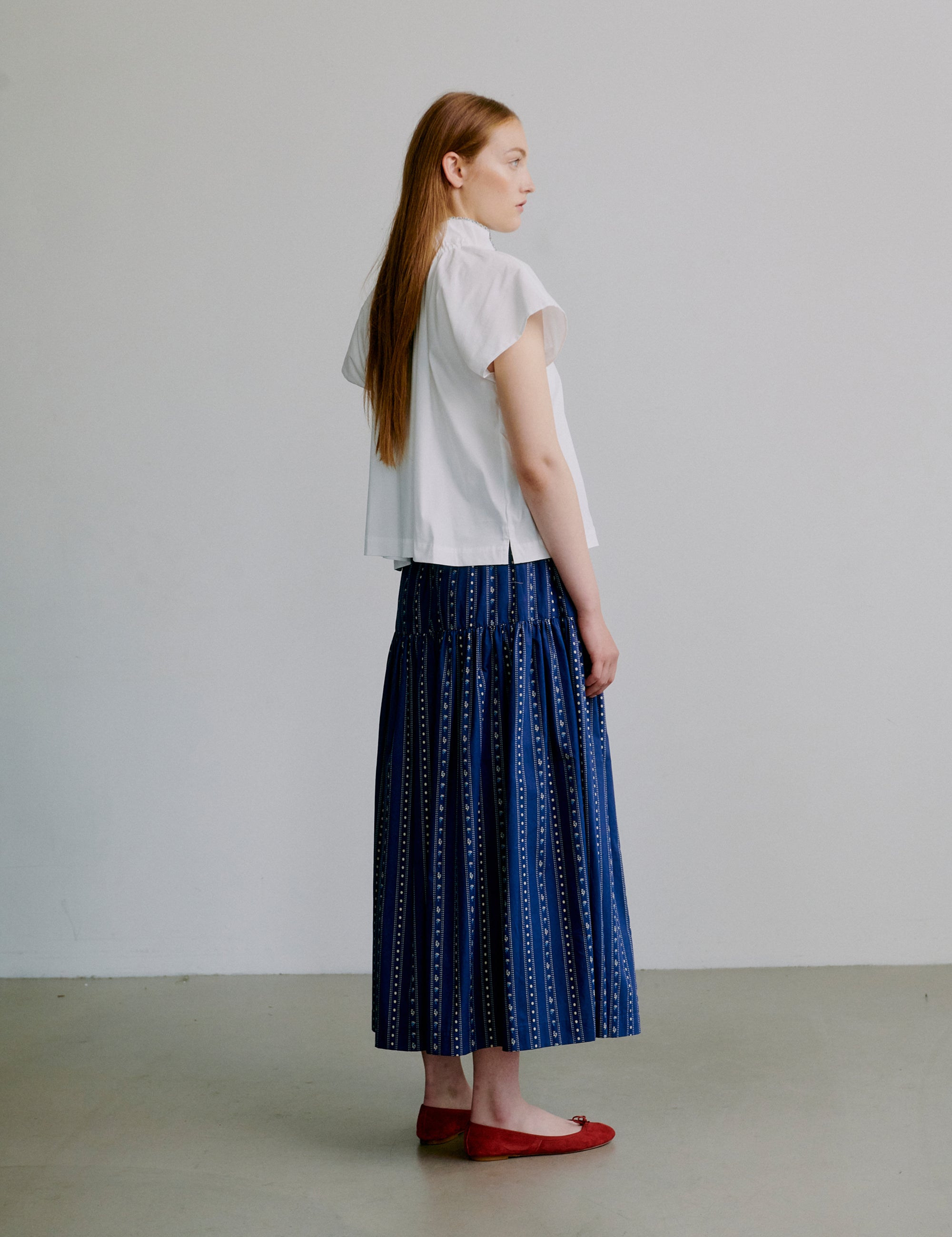 Woman wearing a white shirt and blue patterned skirt