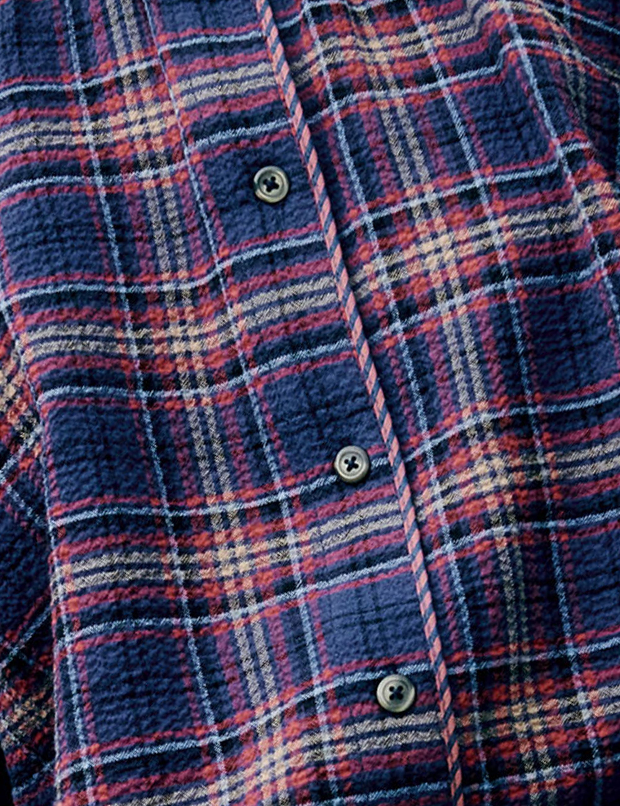 Detail of the dark blue and red checked fabric with buttons of the blouse.