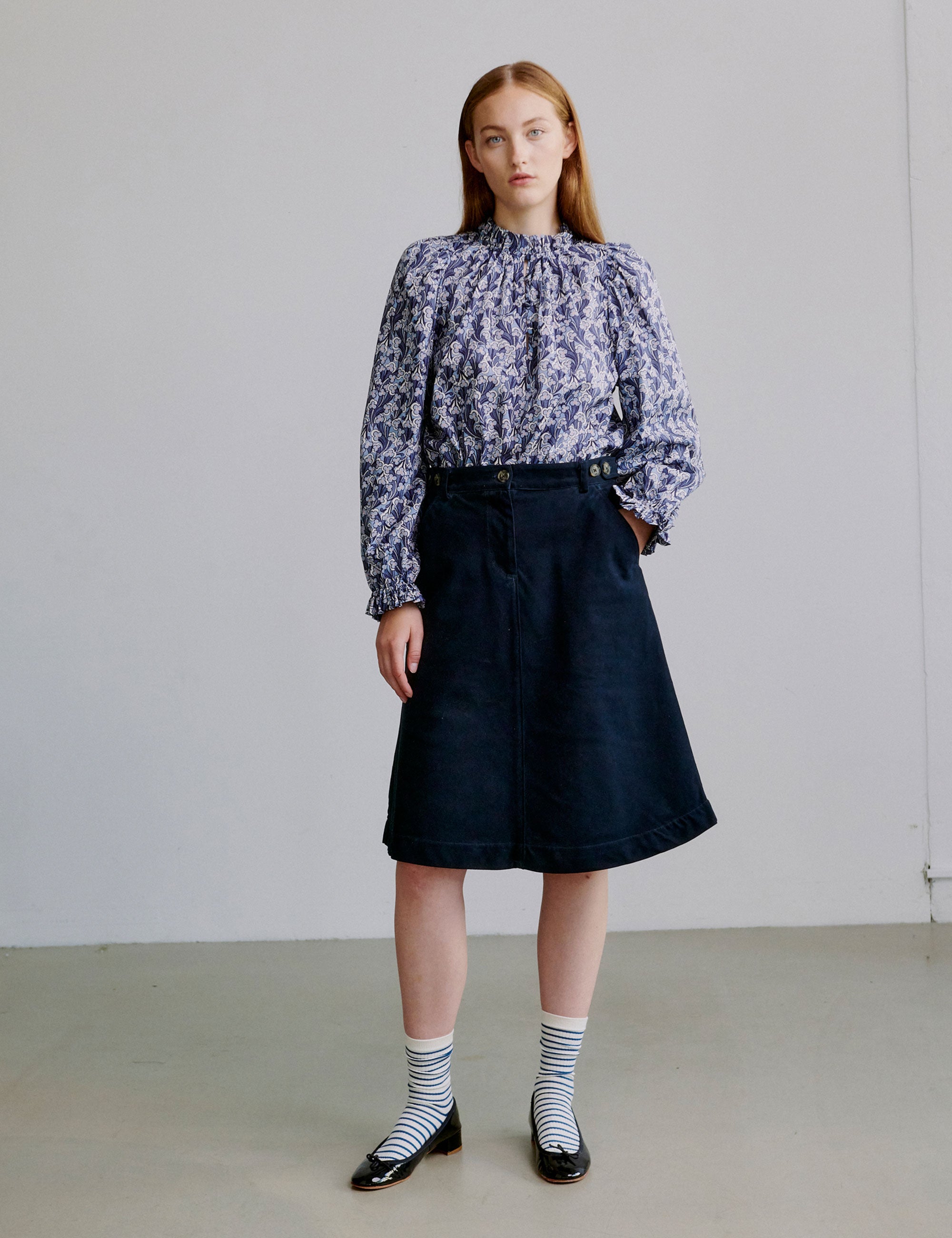 Woman wearing a blue floral blouse and blue a-line skirt